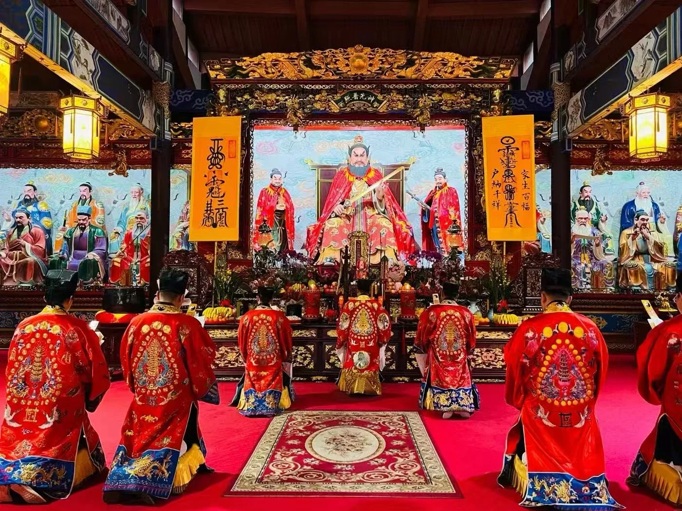 Talisman banners, named deity panels and red ritual robes inside Tianshi Fu at Longhu Mountain