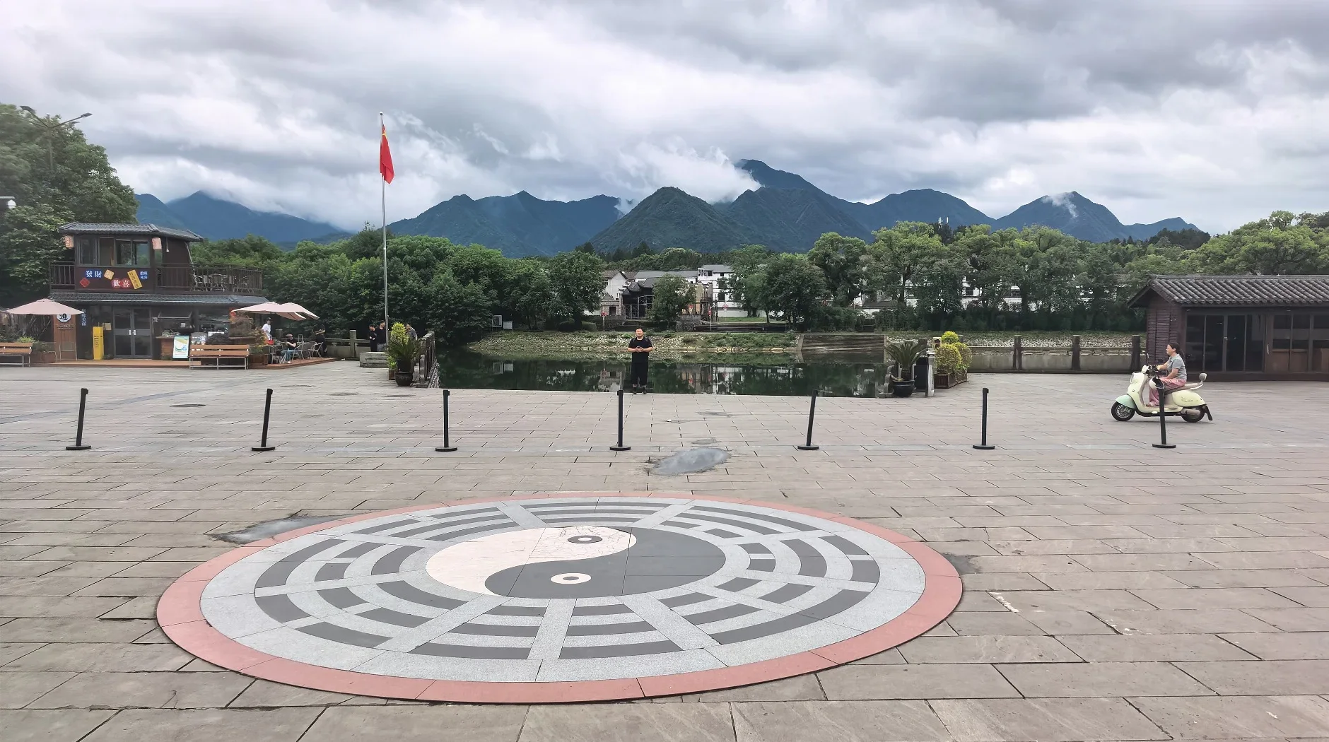 A large black-and-white taijitu set into the open forecourt at Tianshi Fu with the mountain behind it