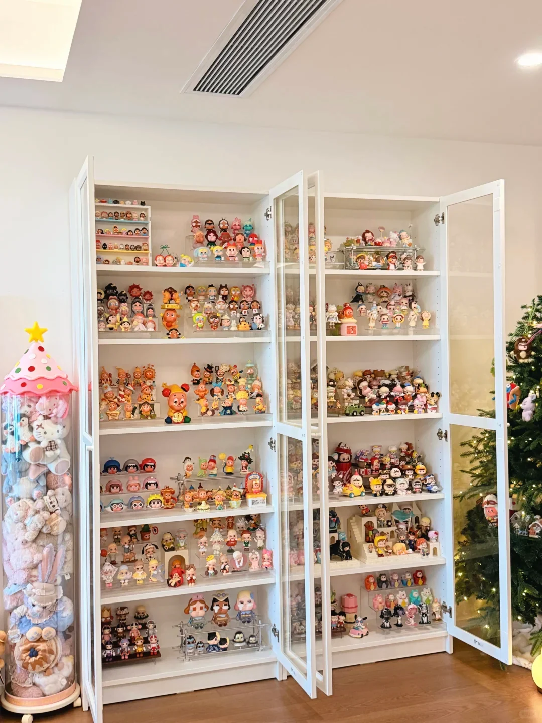 An authorized real Pop Mart cabinet photographed with its doors open, showing multiple character families arranged across full-width shelves