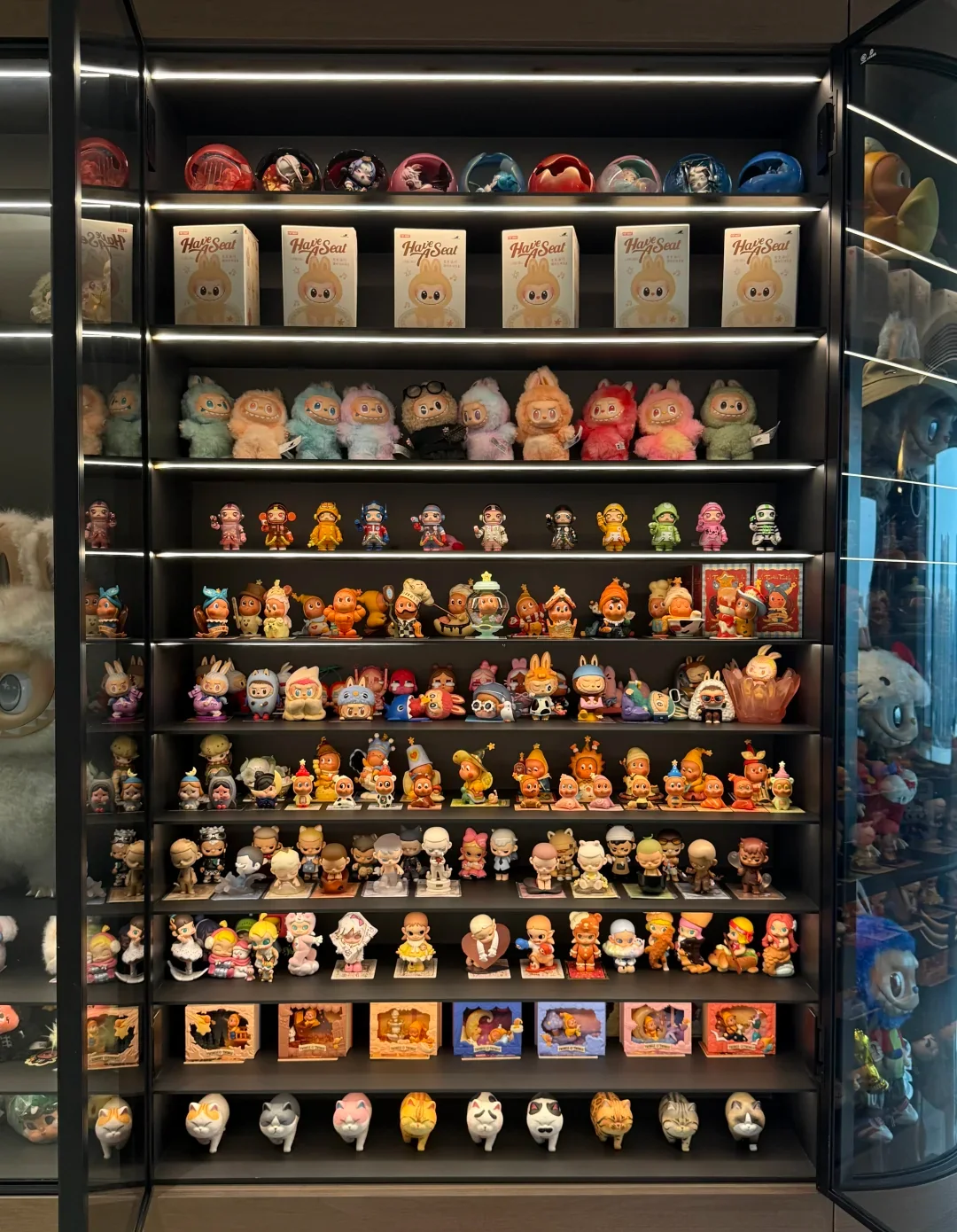 A floor-to-ceiling home display cabinet holding many Pop Mart character families, figures, plush and boxed pieces