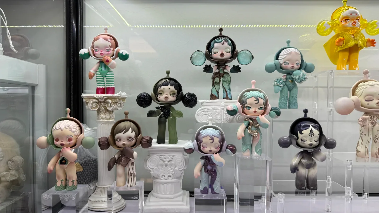 Authorized real SKULLPANDA collection arranged at different heights inside an illuminated glass cabinet