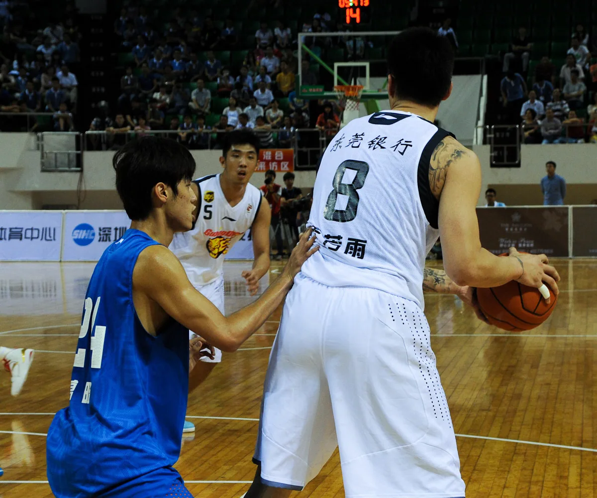 A Guangdong player protects the ball in the post while Shanghai defenders and teammates read the possession