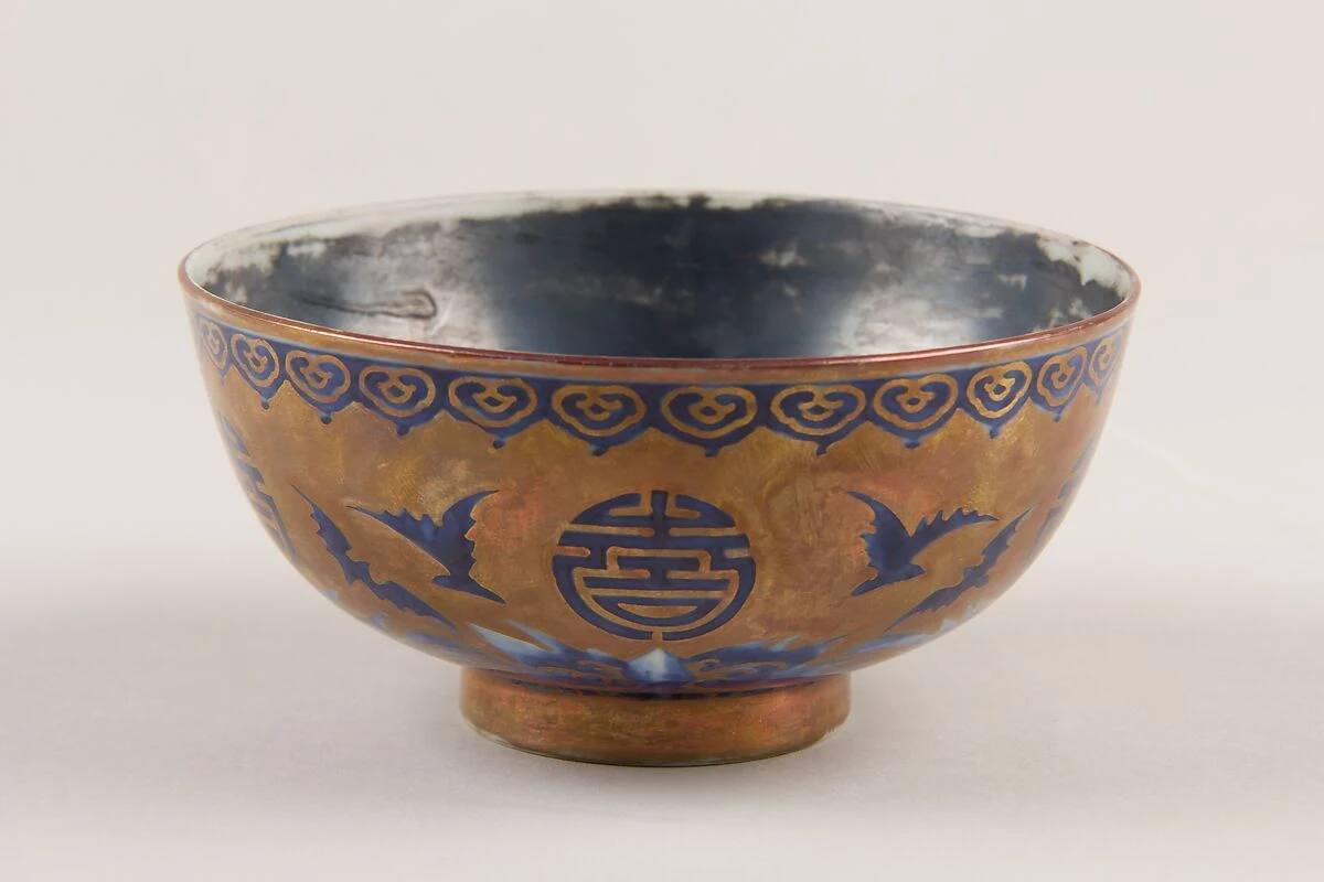 Blue bats flying around gold longevity medallions on a Qing dynasty Chinese porcelain bowl