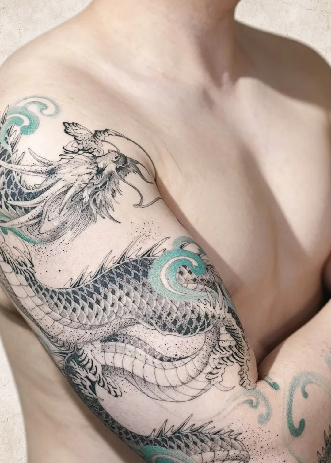 Chinese dragon tattoo meaning in a real cloud-and-dragon sleeve, with a green-blue cloud shape crossing the shoulder