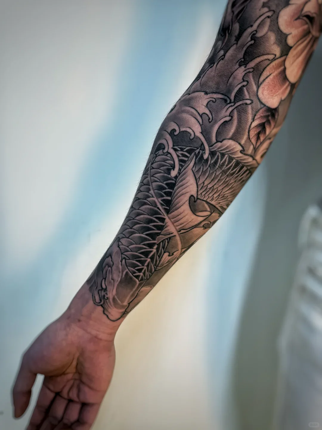 Chinese dragon tattoo meaning comparison: a real black-and-grey koi forearm tattoo, identifiable by its fish head and fins