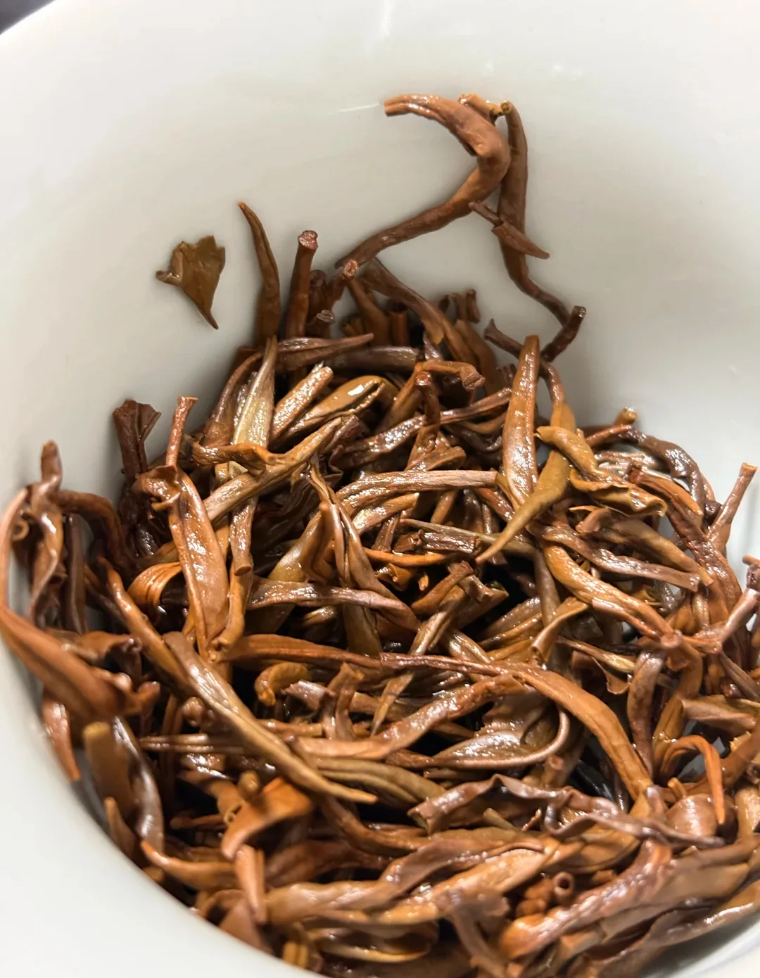 Opened black tea leaves in a white bowl after brewing