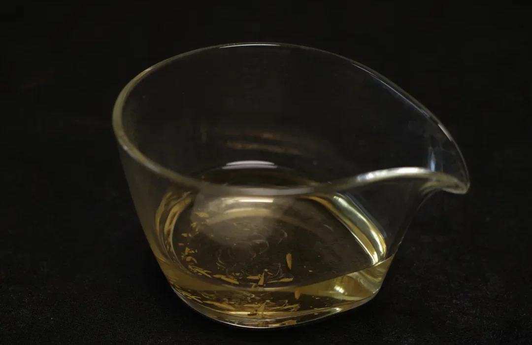 Pale white-tea liquor beside the same brewing setup and visible leaf fragments