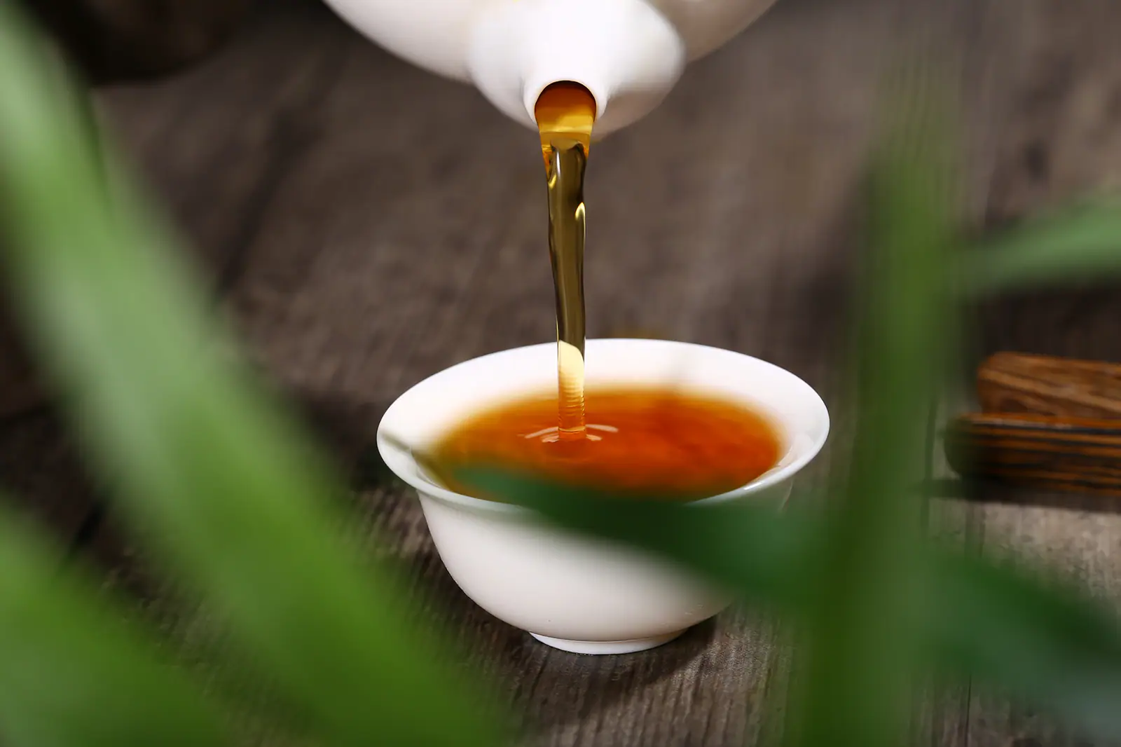 Amber oolong poured into a small cup during controlled service