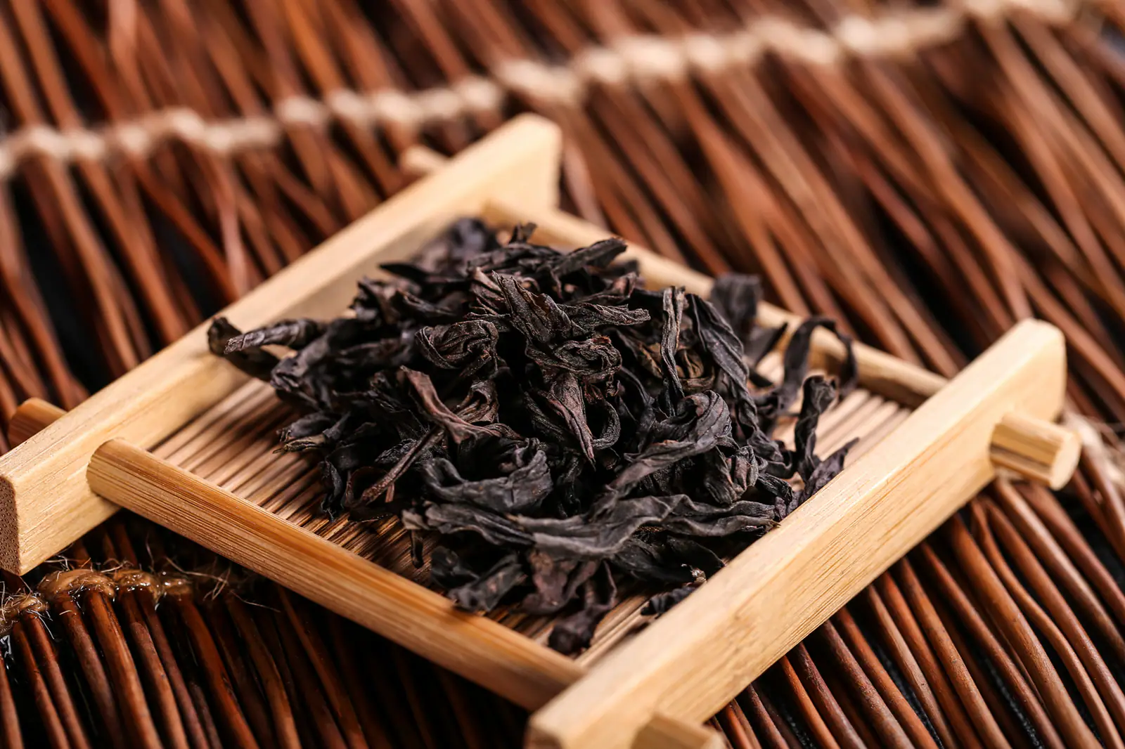 Twisted roasted tea leaves on a bamboo tray, used as general Wuyi oolong leaf context