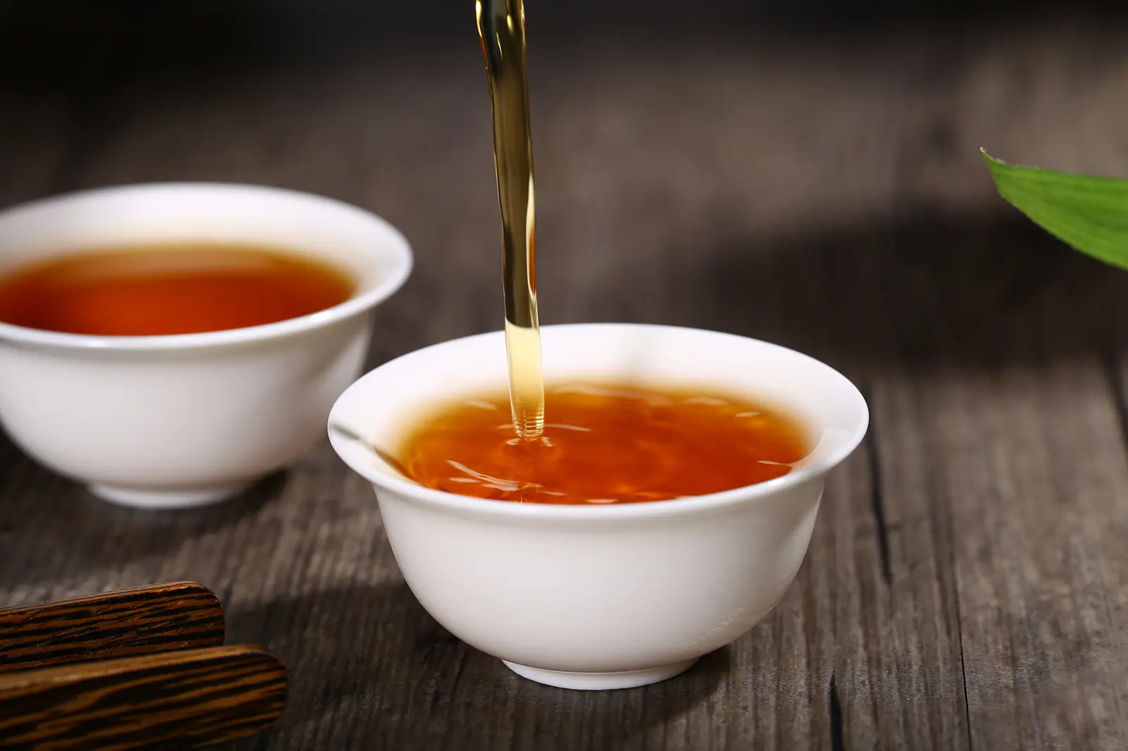 Red-gold tea liquor being poured into a small white cup