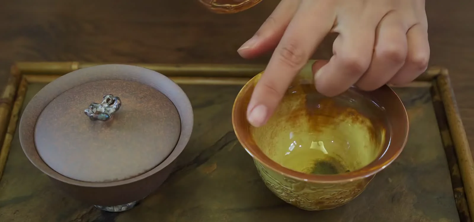 A hand comparing the outward flare and finger clearance of a real gaiwan rim