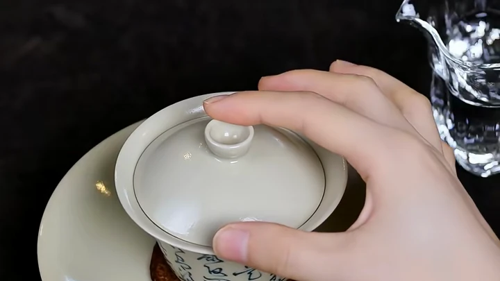 A close overhead view of three fingers controlling the flared rim and lid knob