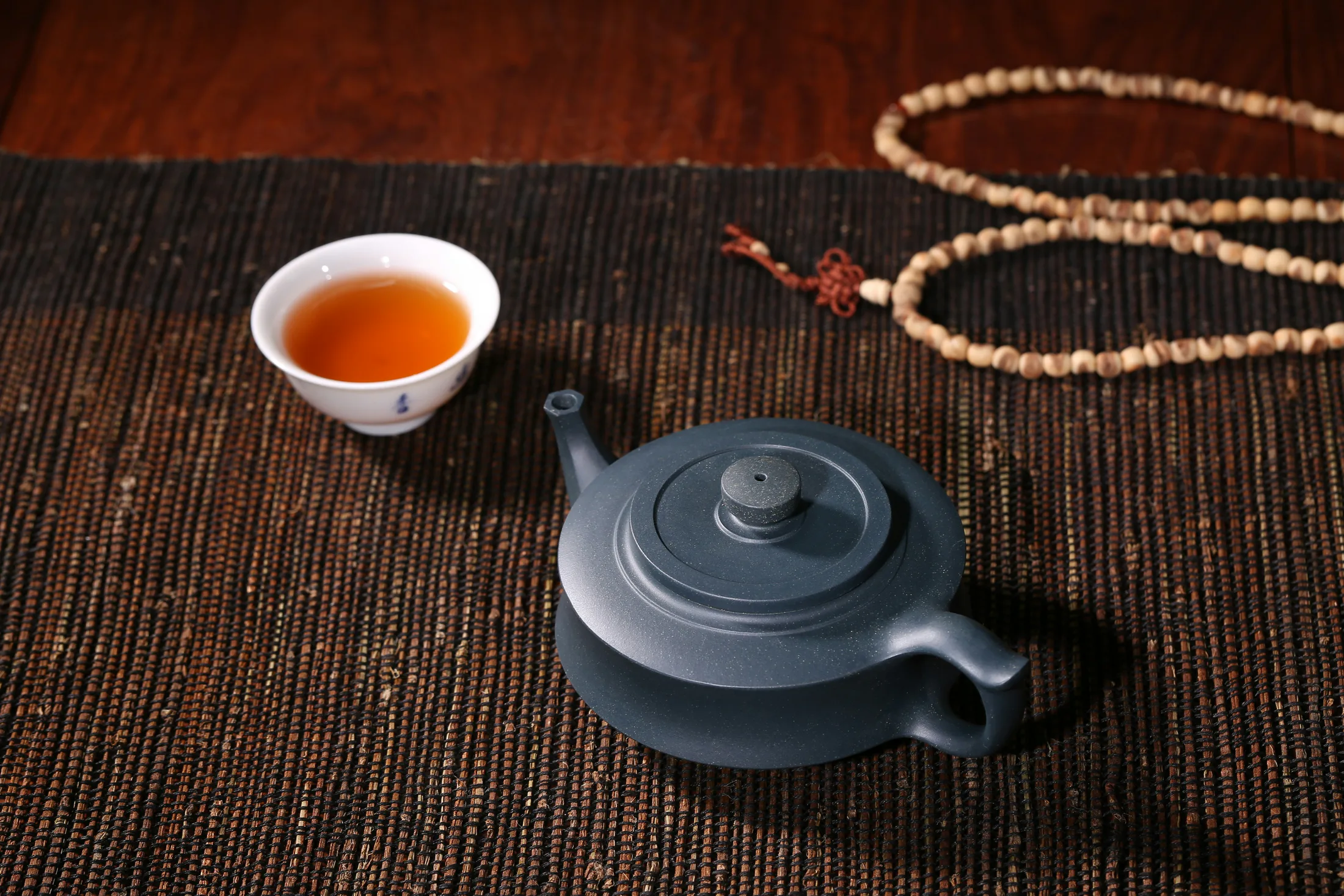 A teapot and cup on a tea table, showing a contrasting vessel context
