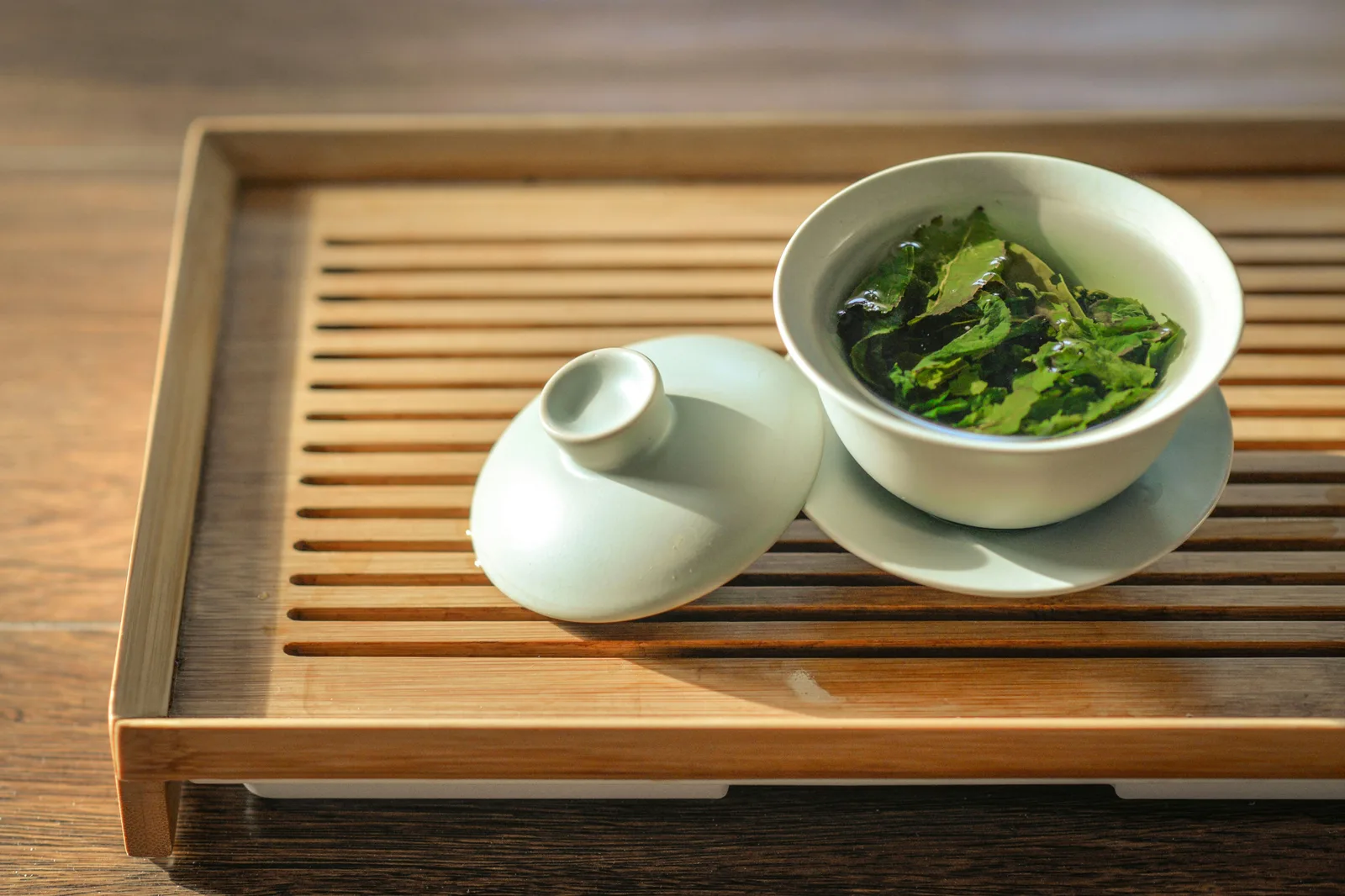 Expanded real tea leaves visible in an open white gaiwan after infusion