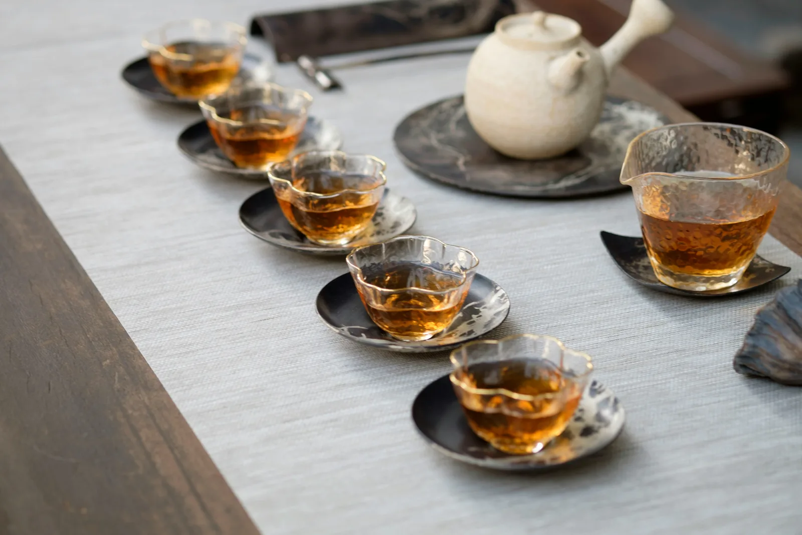 A white teapot, pitcher and six filled cups arranged after shared service