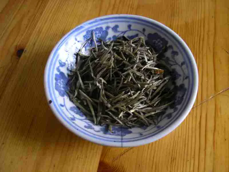 Junshan Yinzhen tea buds photographed in a blue and white bowl