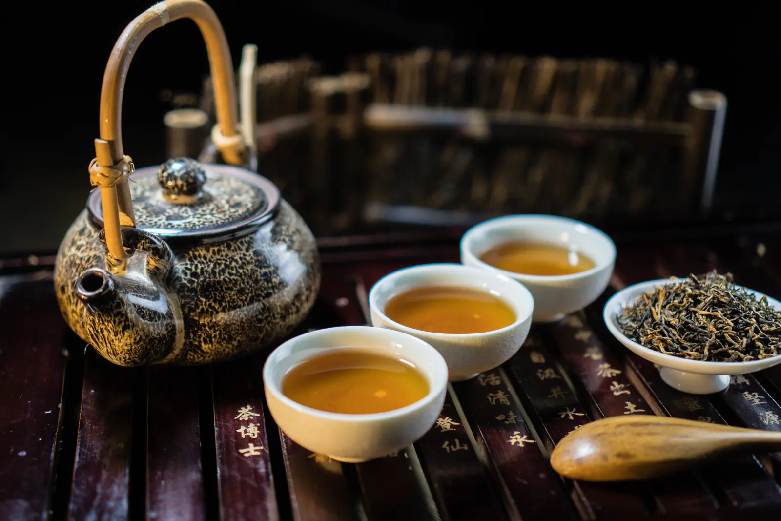 A dark teapot and several cups showing a calm black-tea service suitable for Keemun