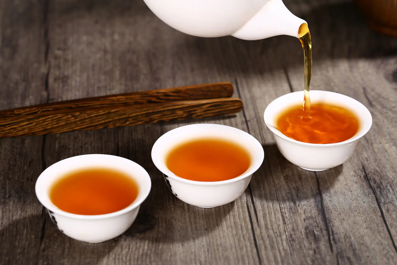 Amber black tea poured across several small cups, showing how equal service supports comparison