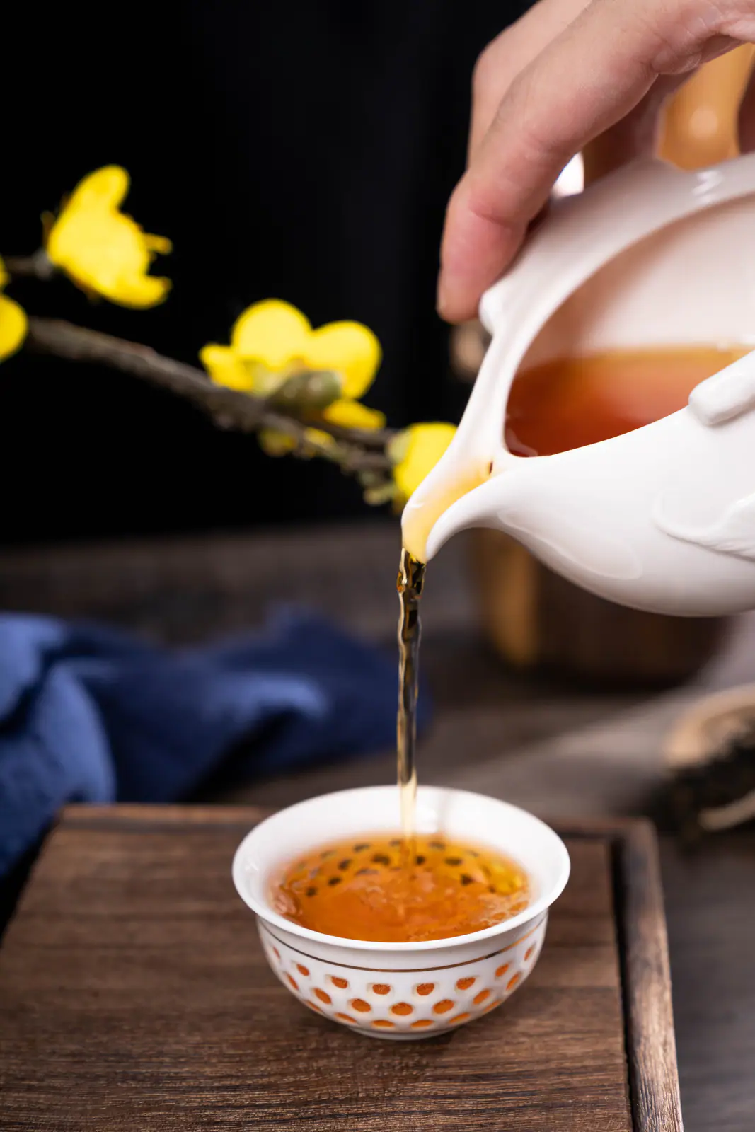 Amber tea poured into a small cup, showing how controlled service helps separate smoke from liquor texture