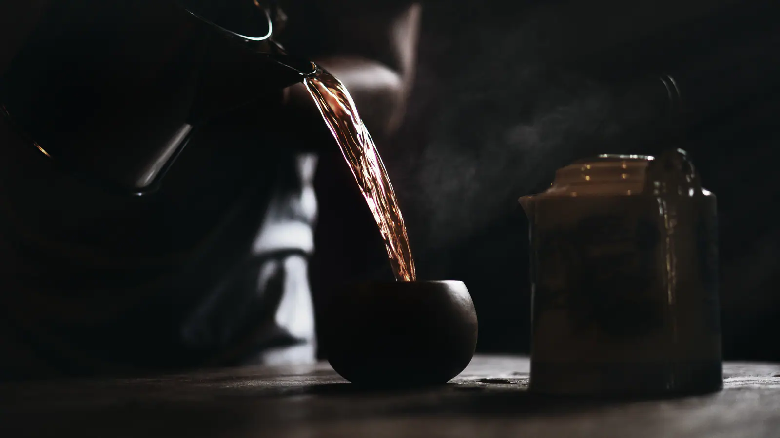 A dark tea pour photographed in low light, showing the visual weight of a smoky black-tea session