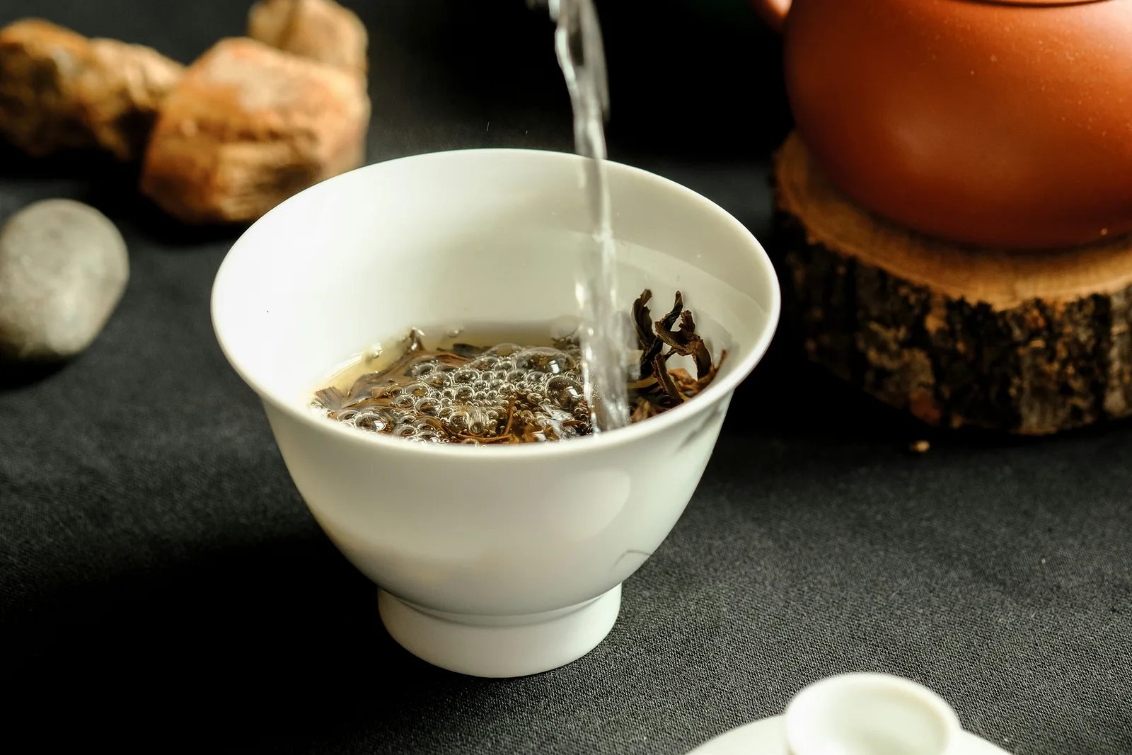 Hot water entering a white gaiwan during a measured tea-brewing session