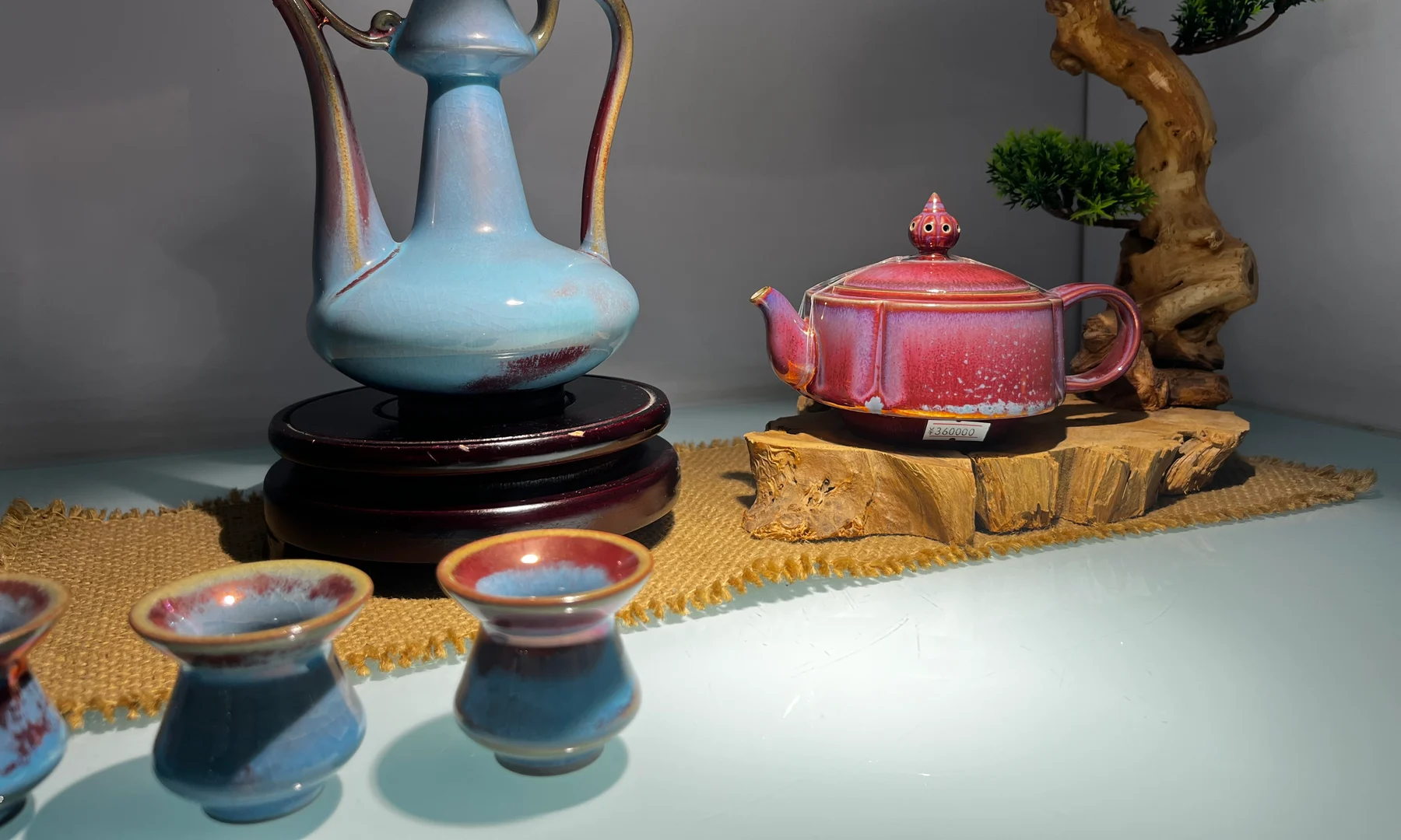 A first-hand Jun-glazed porcelain tea display with a lidded teapot, three cups and another tall pouring vessel at the Jun Ceramic Culture Park