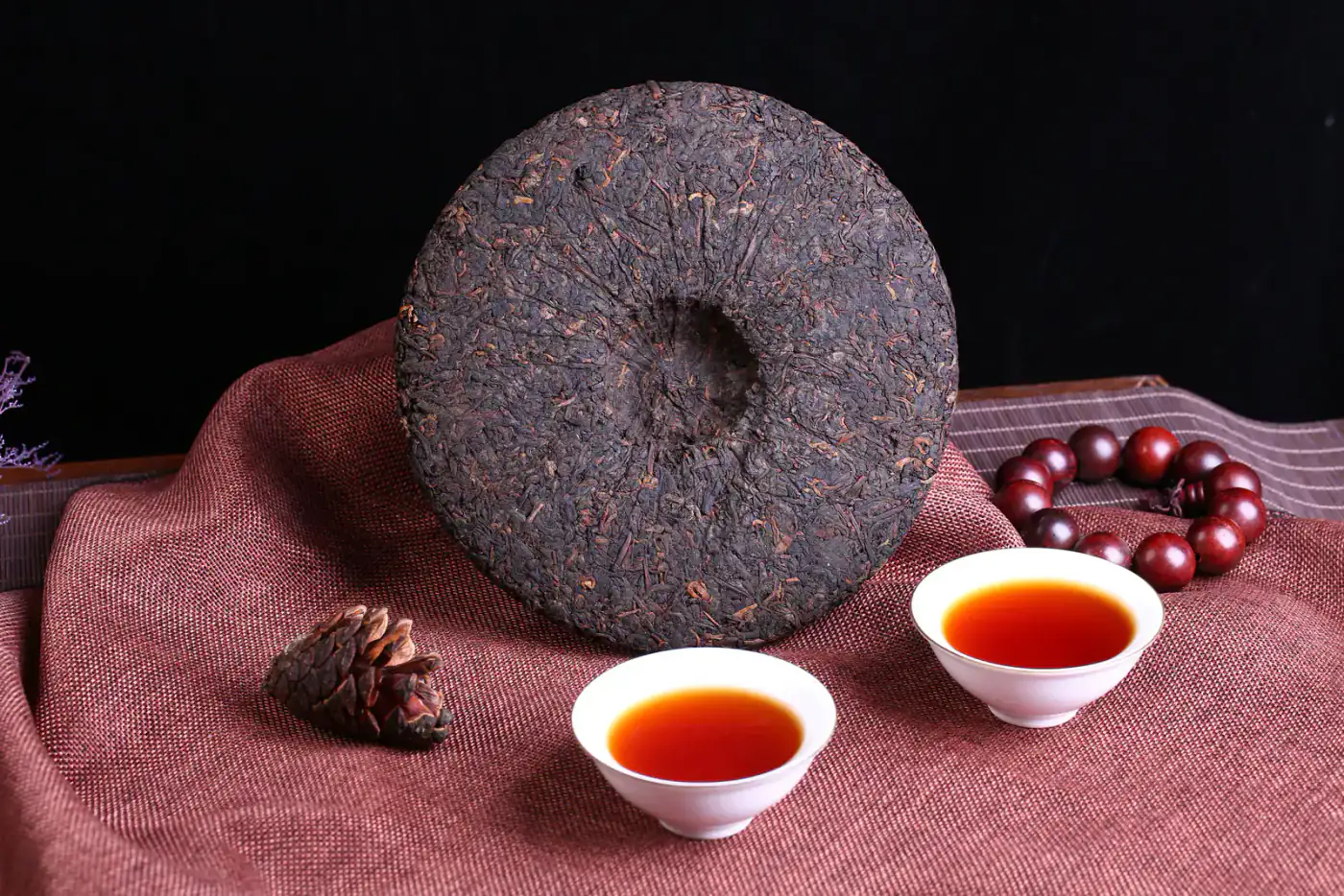 A compressed Pu-erh cake with cups showing the form that must be opened before even extraction