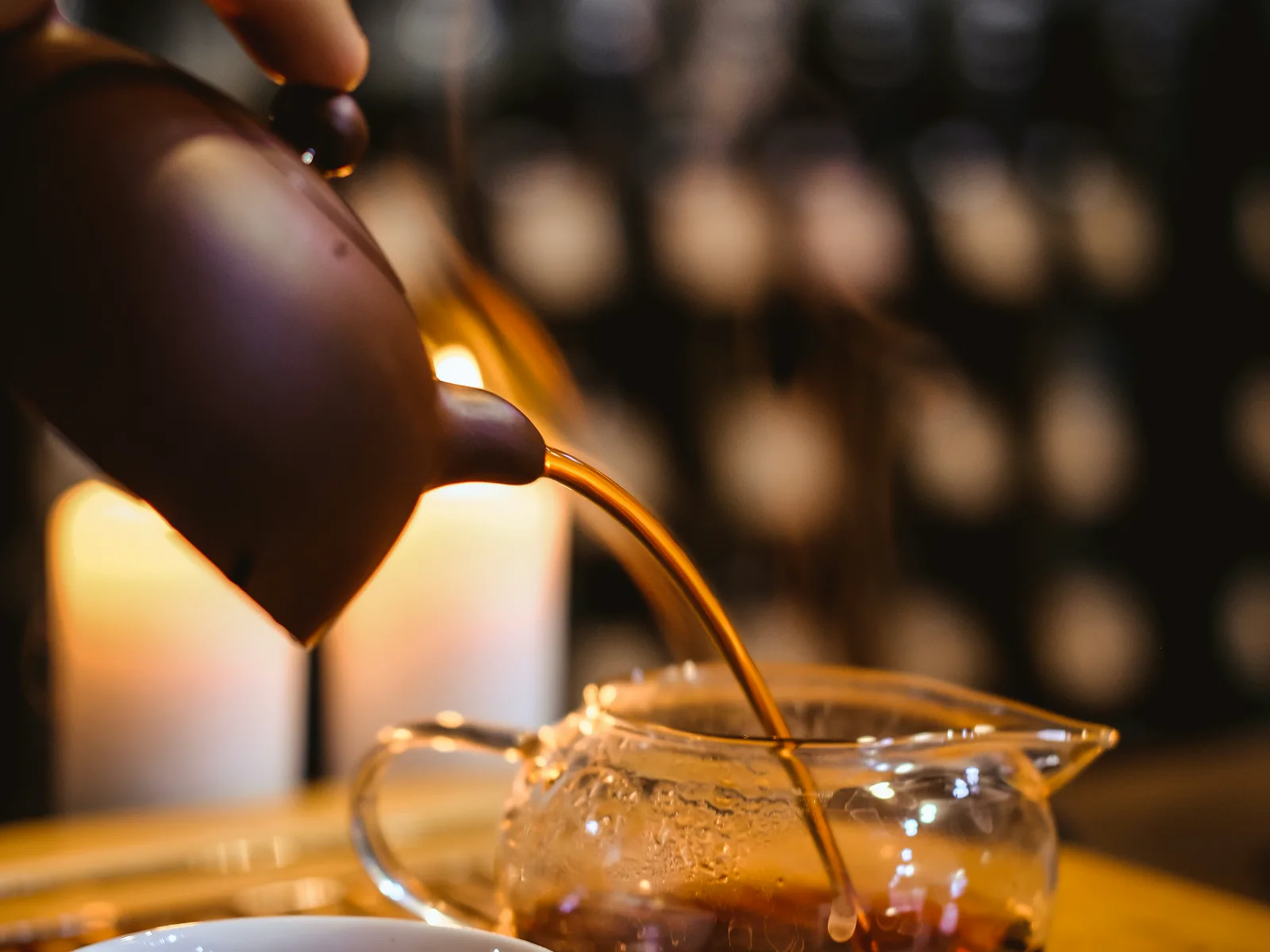 Dark Chinese tea being poured into a sharing pitcher during repeated infusions