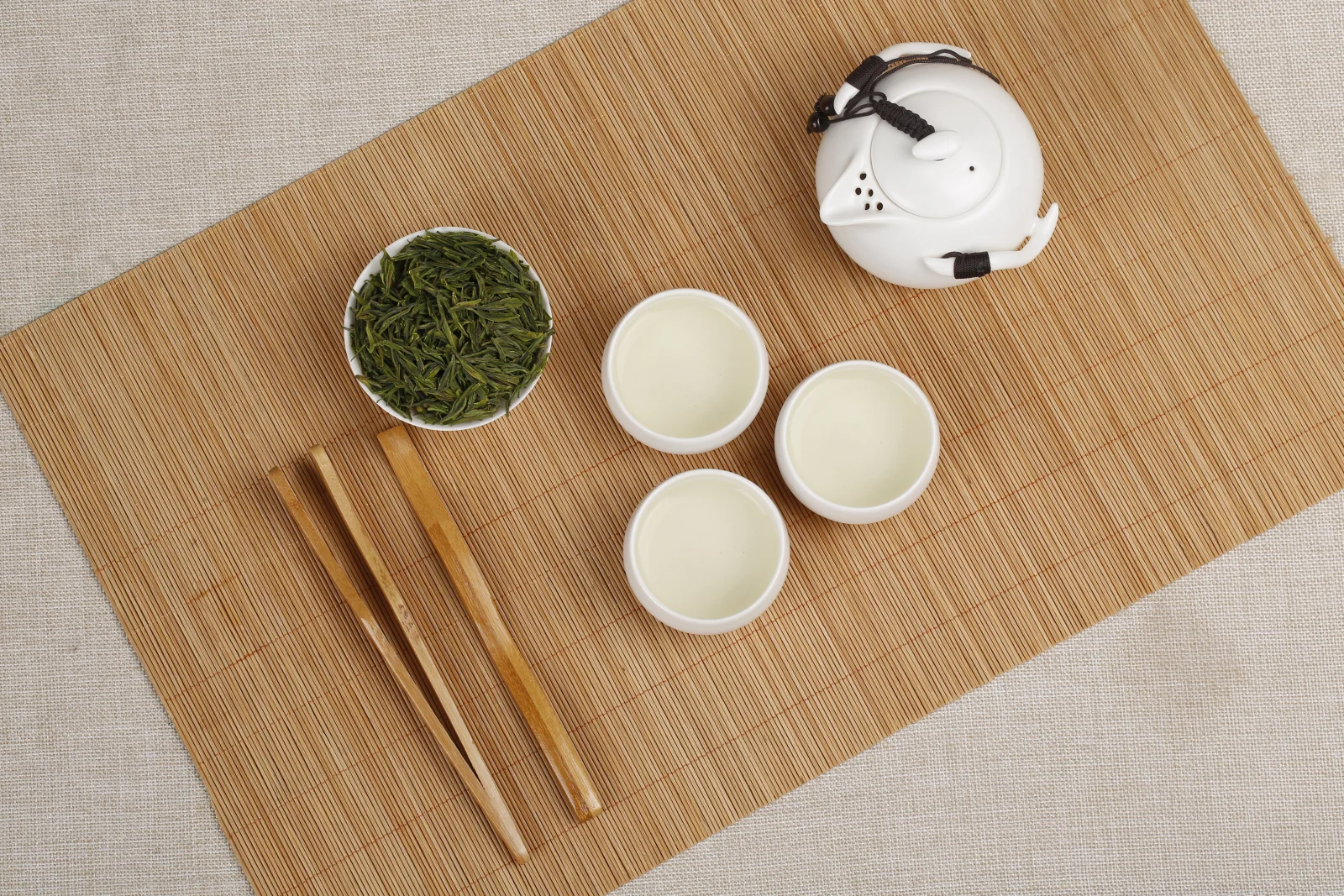 Three small white Chinese tea cups served from one white teapot