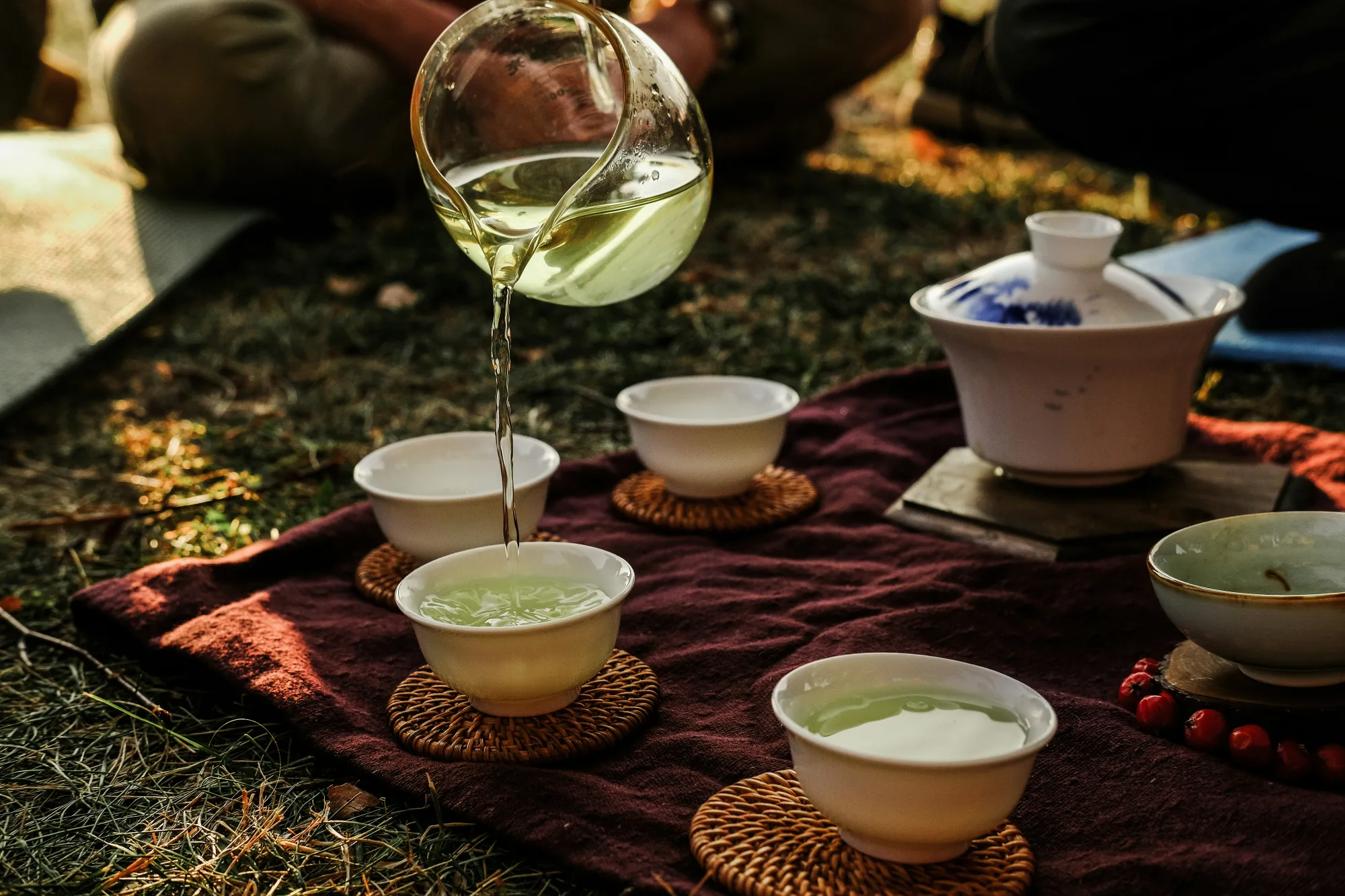 A working Chinese tea set with a covered gaiwan, glass fairness pitcher and several porcelain cups during service