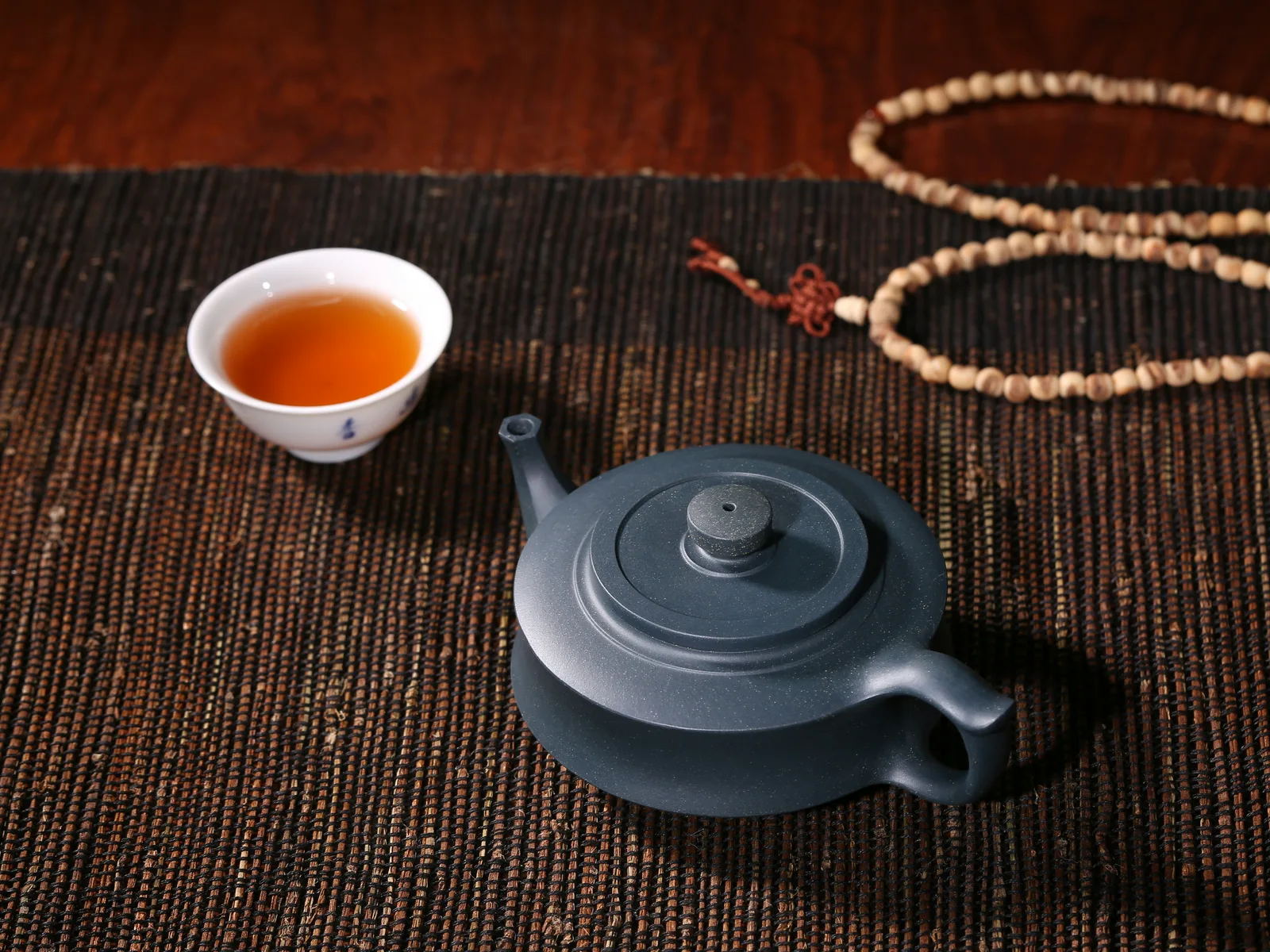 A dark teapot and small cup arranged for repeated Chinese tea infusions