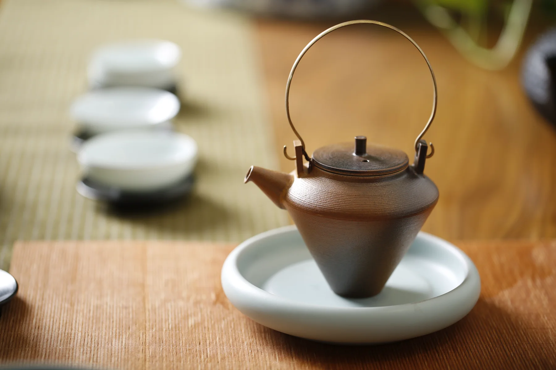 A compact handled pot and small cups arranged for tea service
