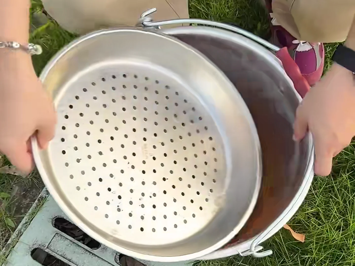 A perforated insert lifted to reveal used liquid collected in the container below