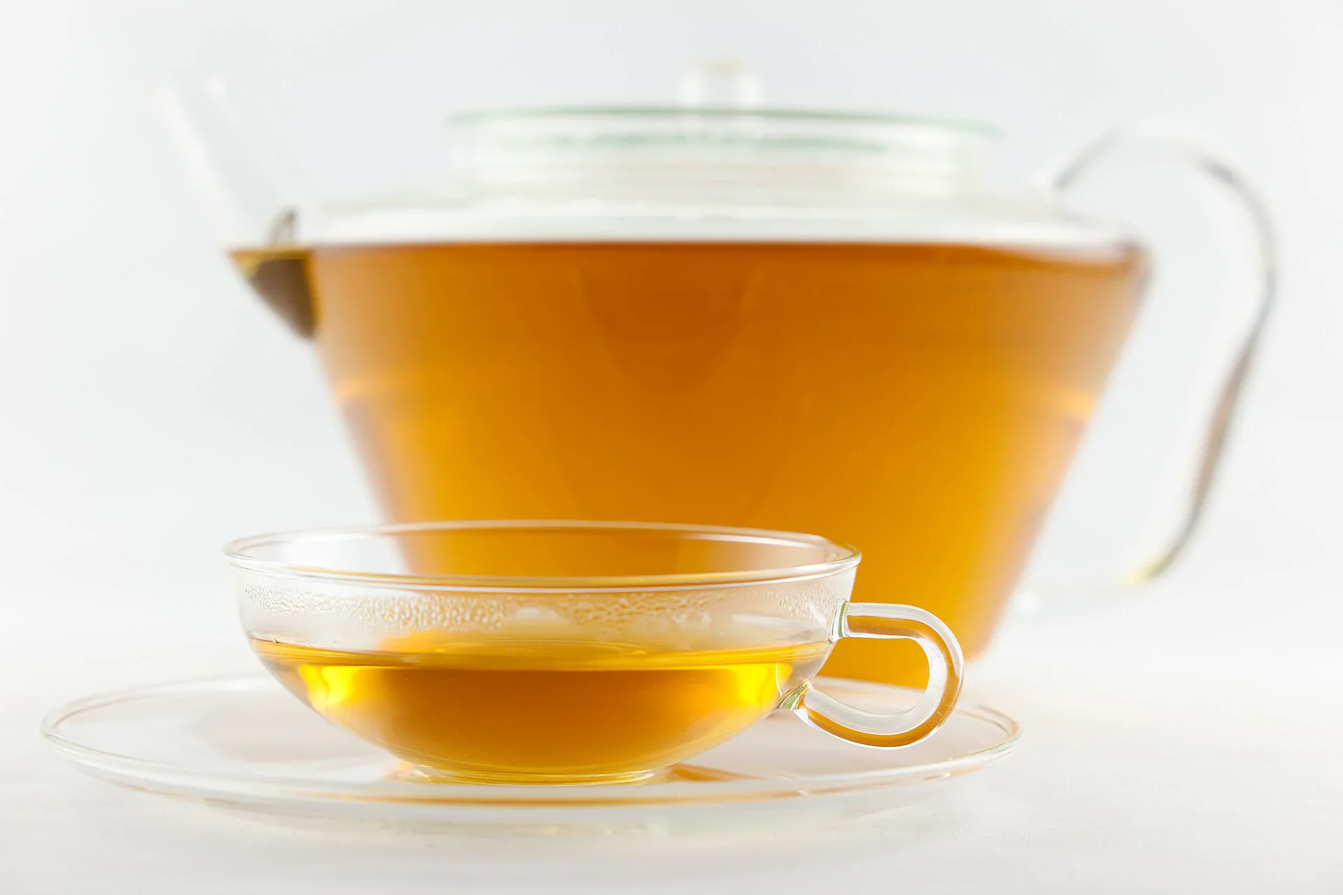 Freshly brewed White Peony tea in a clear glass cup and teapot
