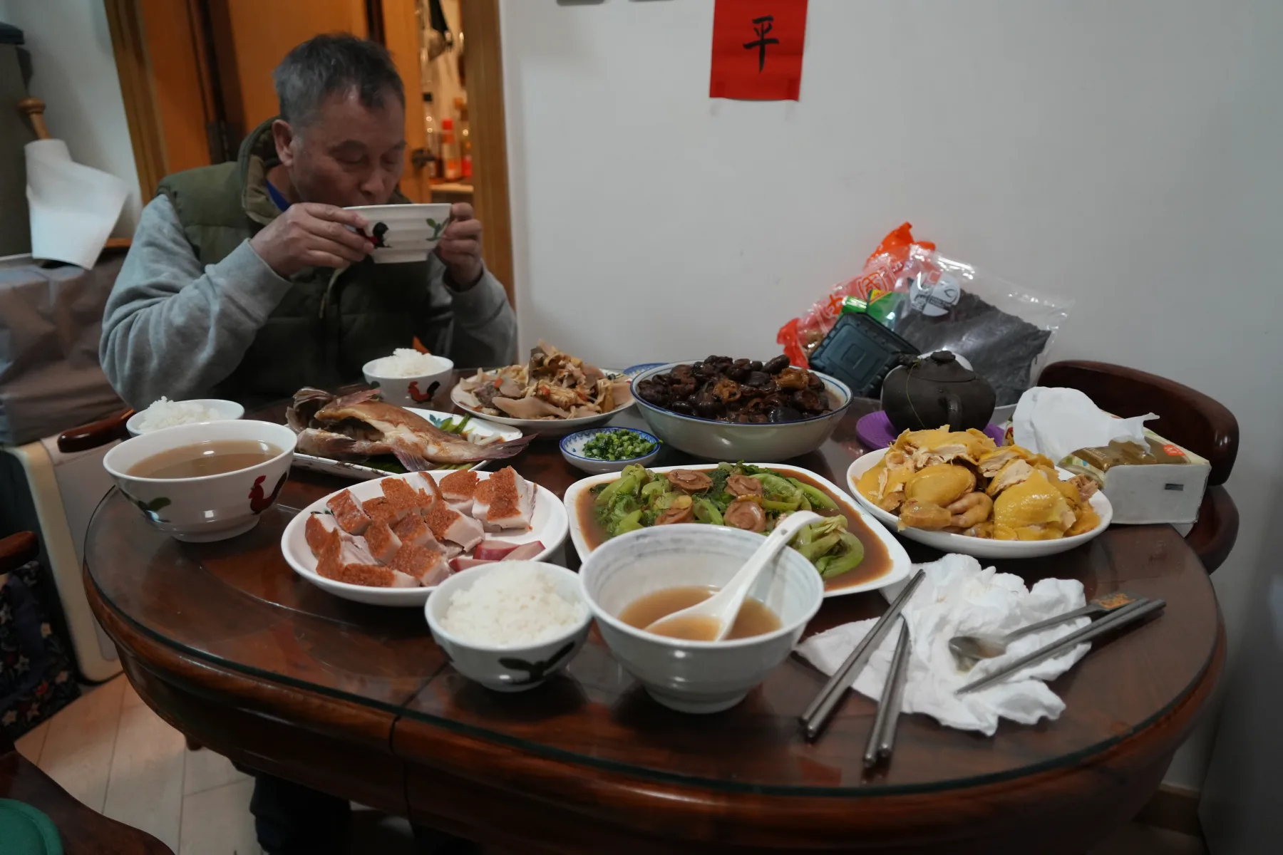 A person seated at a home table with several dishes during the Chinese New Year holiday