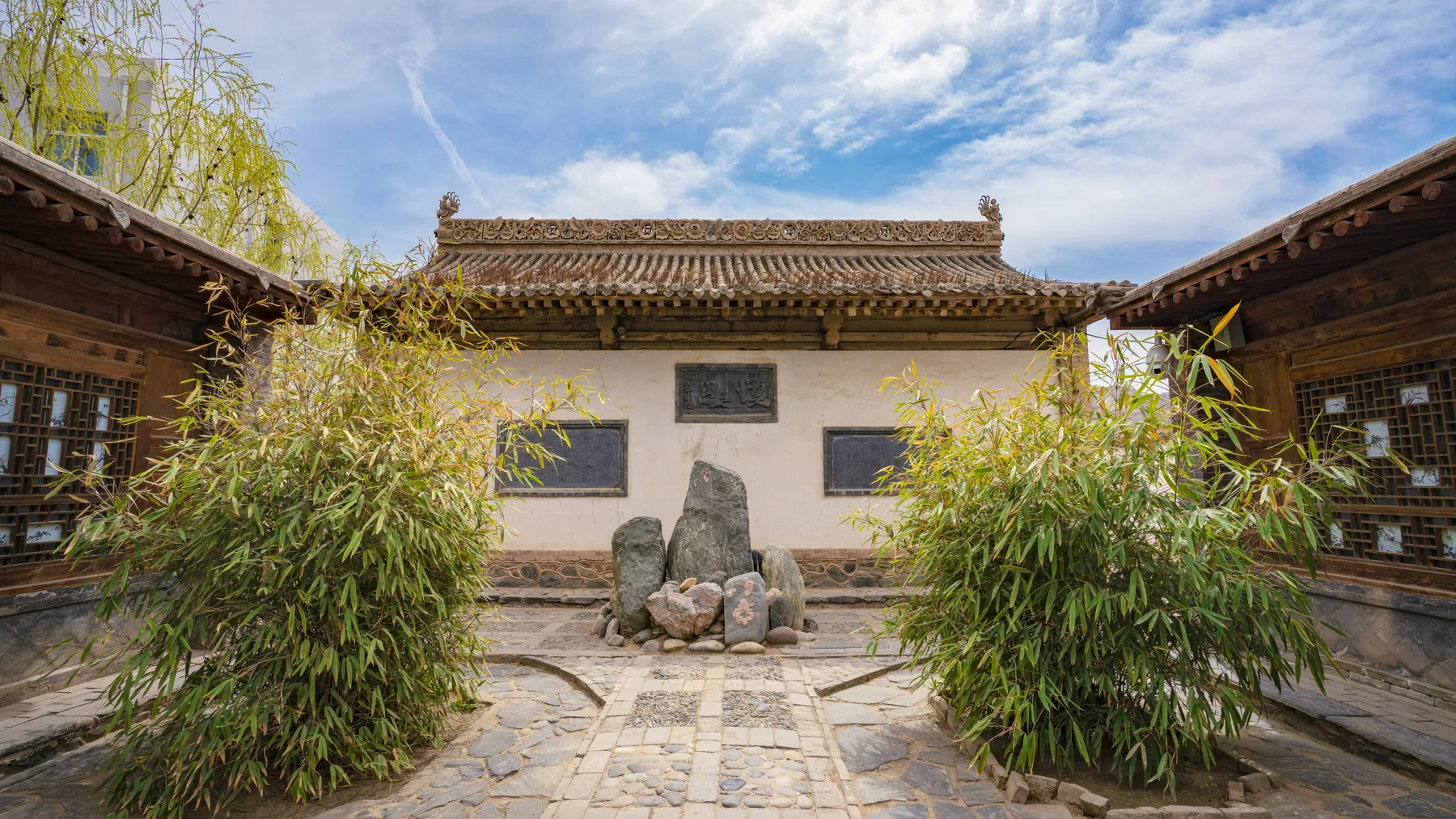 A timber ancestral-hall courtyard in Qingcheng, Gansu, framed by bamboo and stone tablets