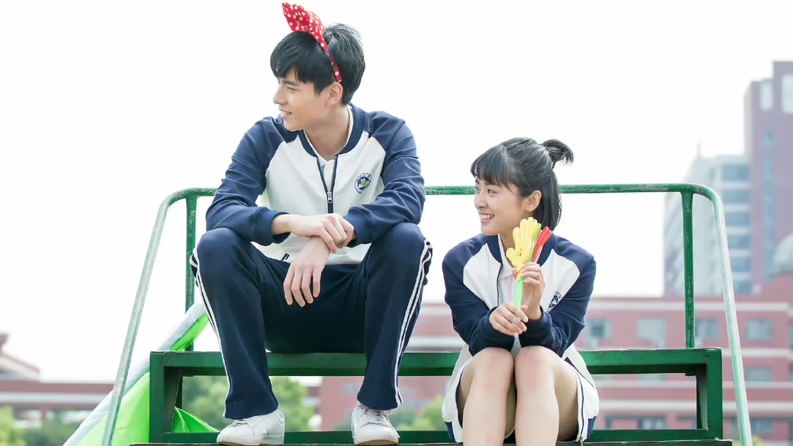 Chen Xiaoxi and Jiang Chen sitting apart on green campus bleachers during the school years in A Love So Beautiful