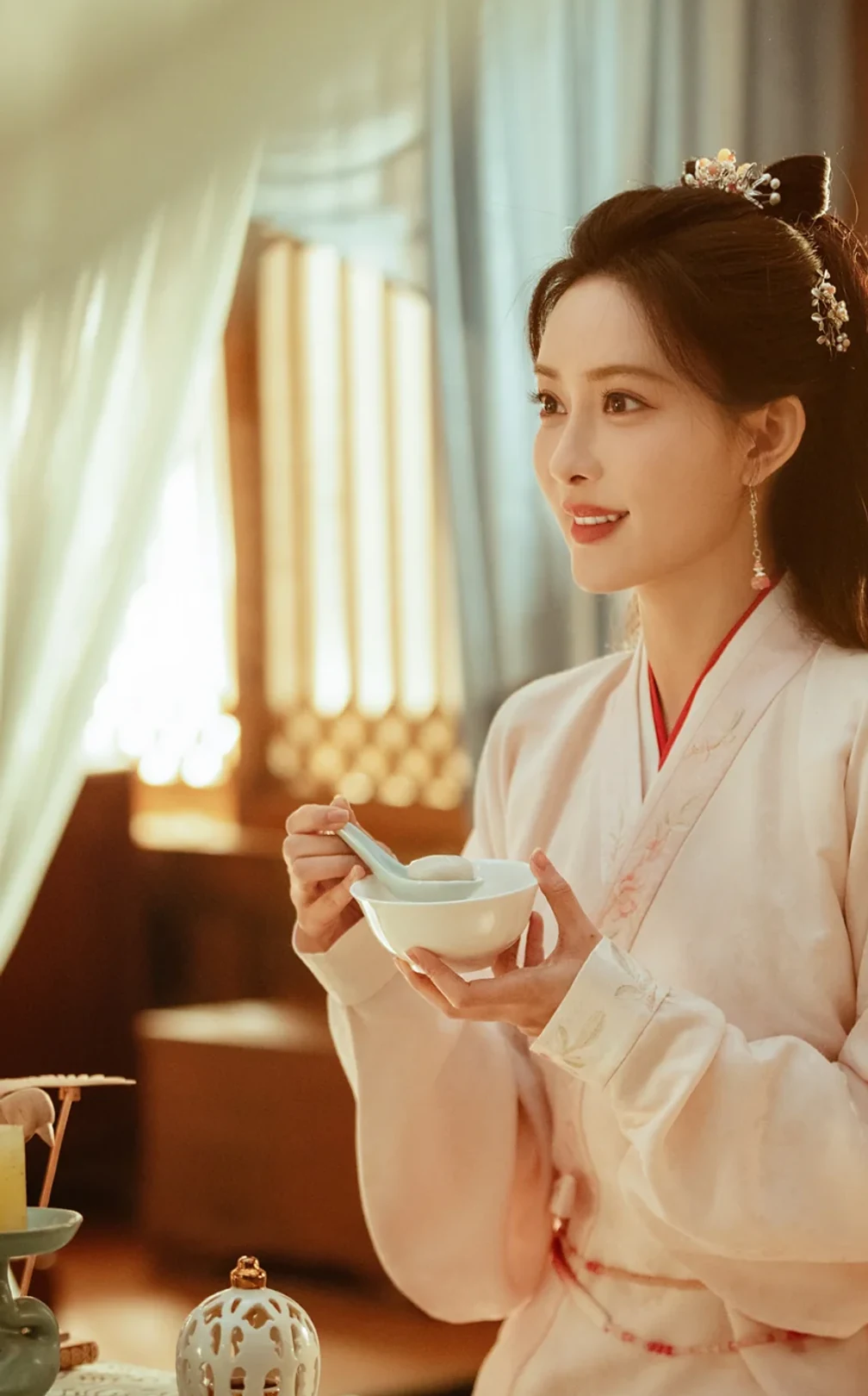 Dou Zhao holds a bowl in a warm interior in an authorized still from Blossom Chinese drama