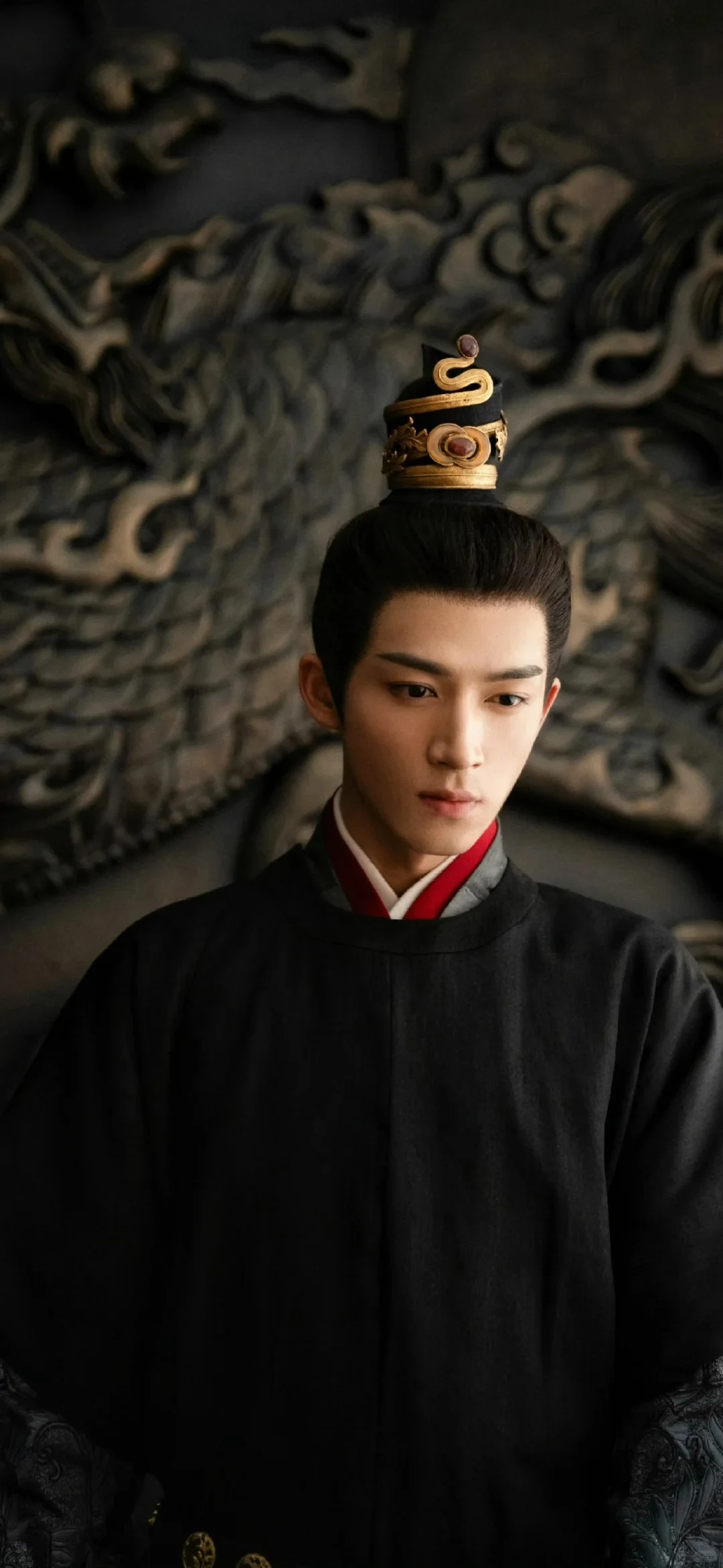 Wang Xingyue as Duke Su in black and red court costume before a carved dragon relief