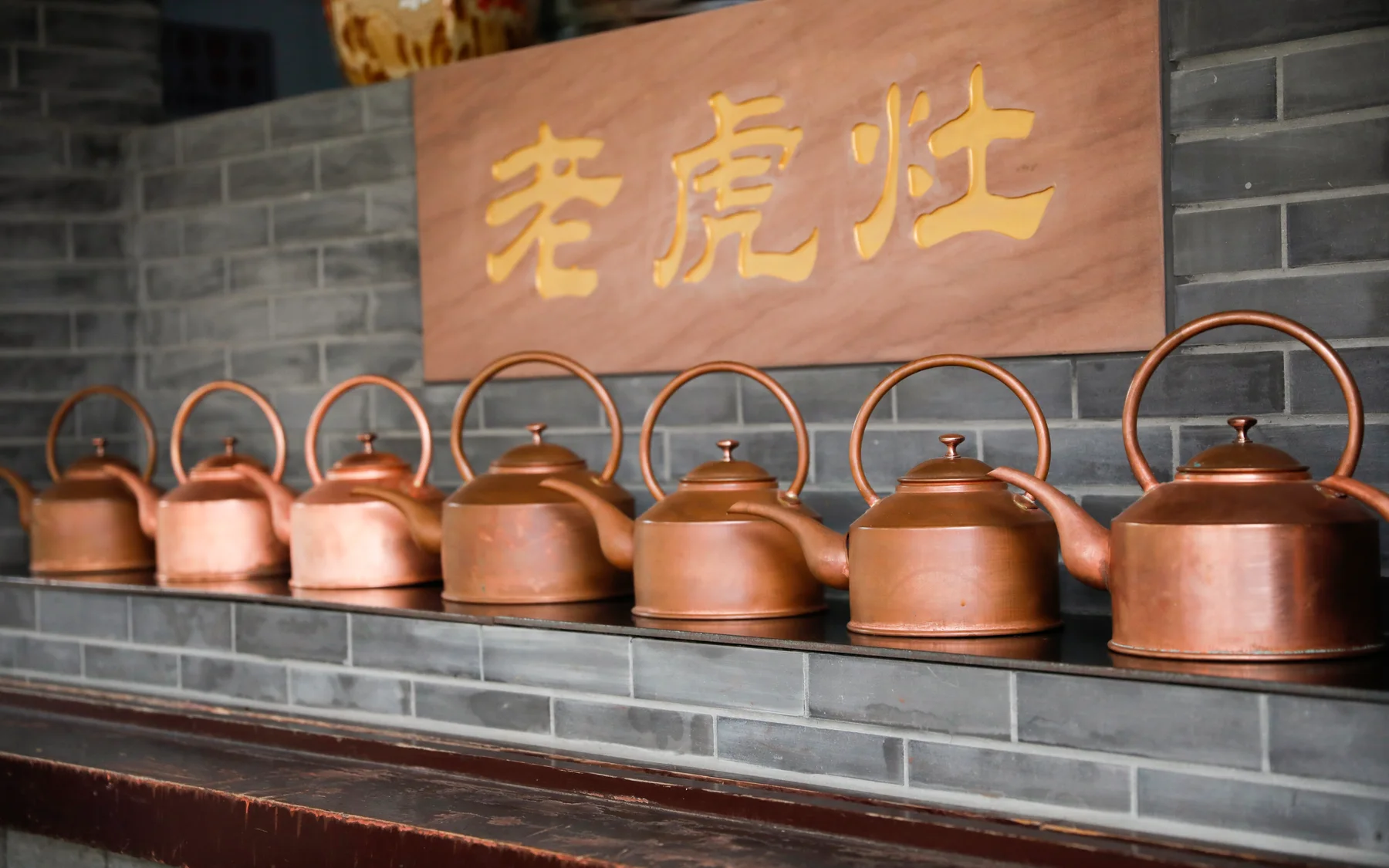 A row of copper kettles at a Chengdu tea-house hot-water station, evidence that even a relaxed cup depends on a practiced service rhythm