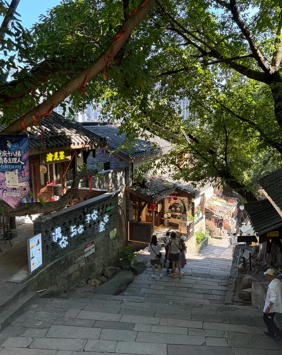 A lived Chongqing old-street stairway descending through shops, trees and several visible levels