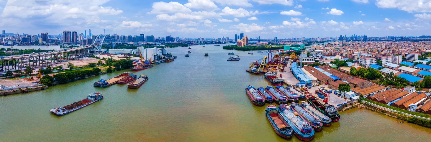 Cargo vessels, cranes and warehouses along a working Guangzhou waterway