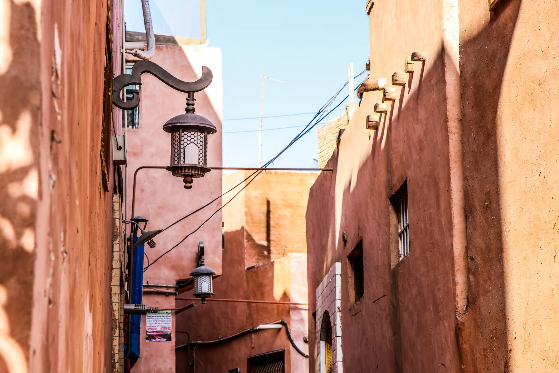 Sunlit walls, utility lines and lamps along a lane in Kashgar's old city