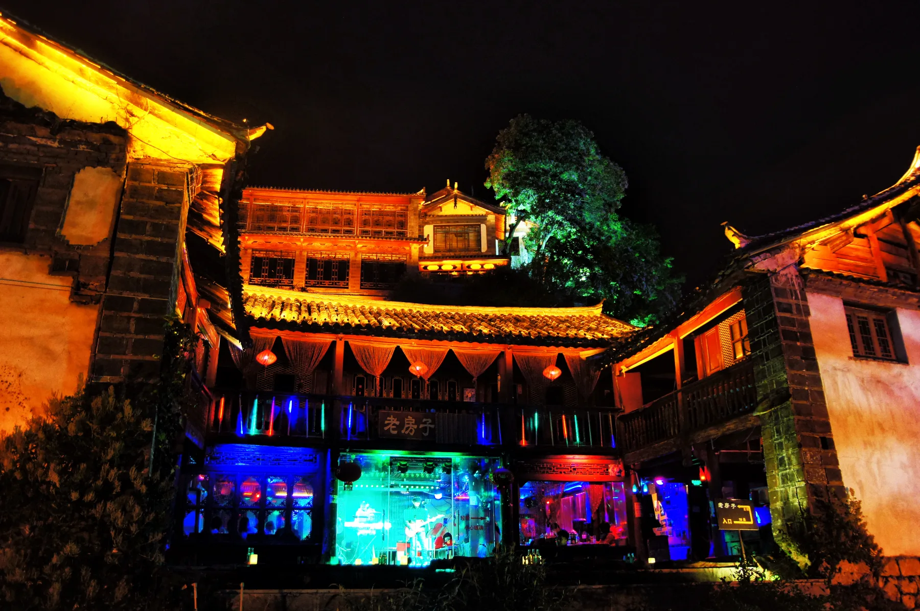 Bars and illuminated timber buildings showing the commercial night side of Lijiang Old Town