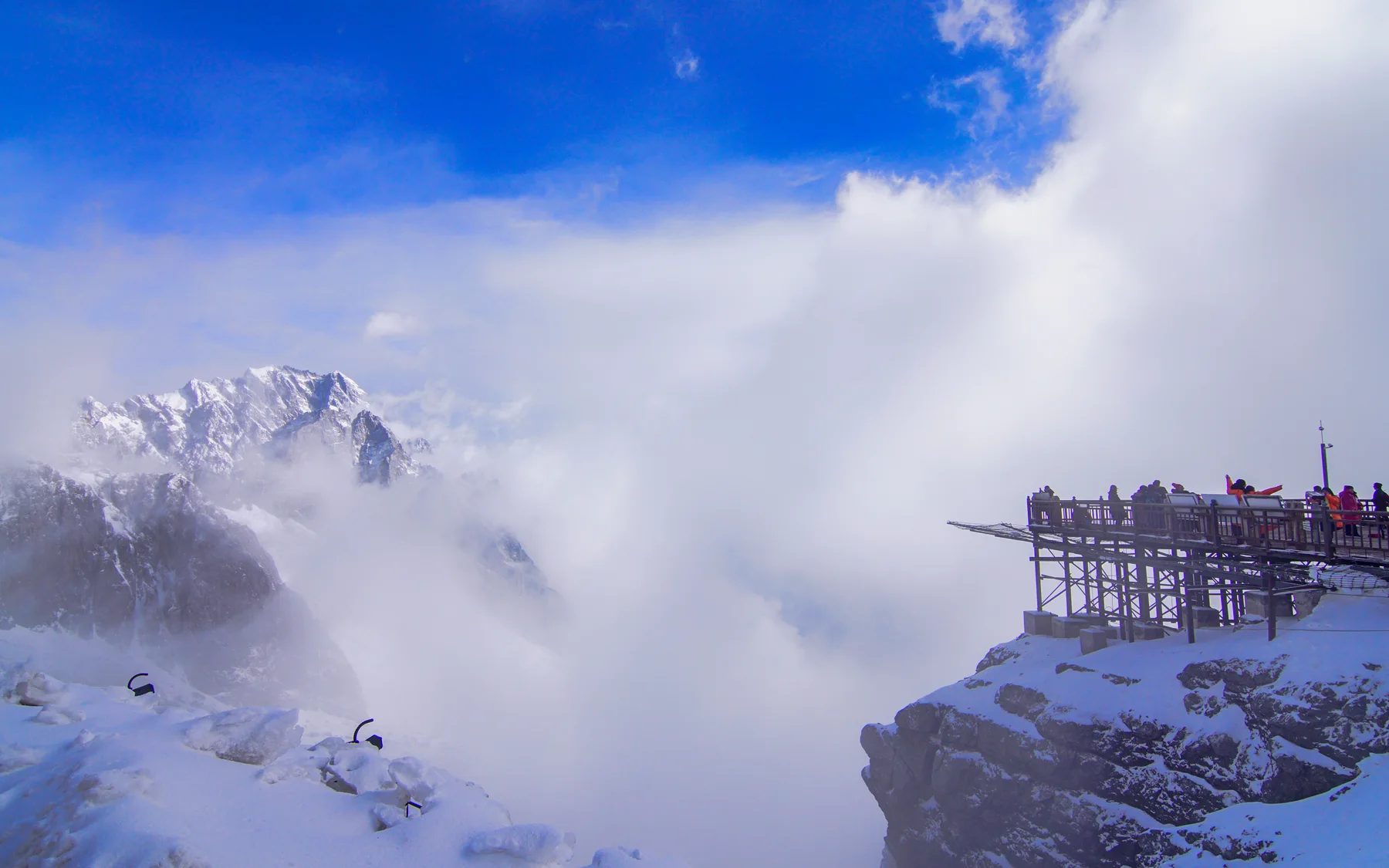 Jade Dragon Snow Mountain viewed from a visitor platform where weather and crowd conditions determine the experience