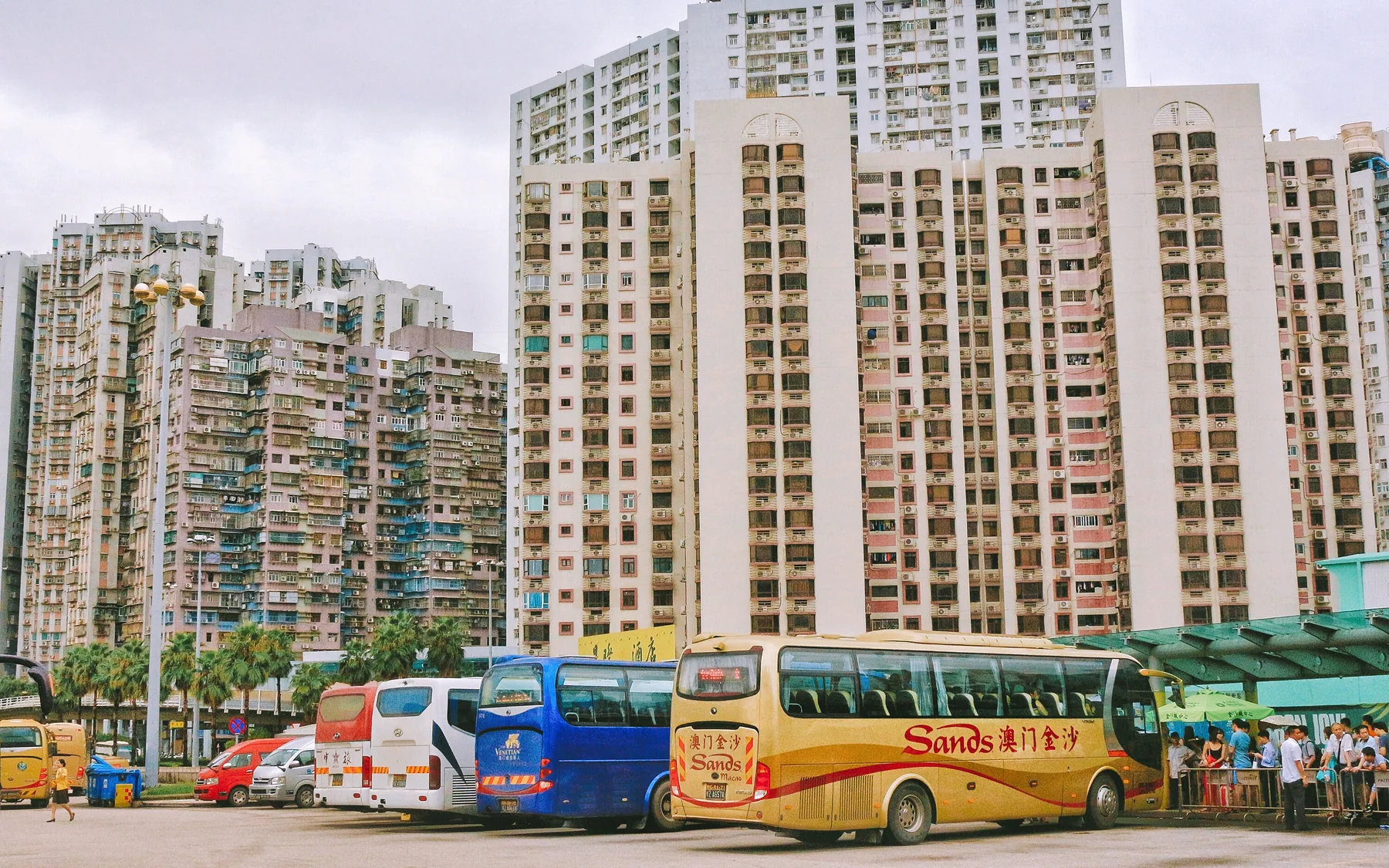 Tour coaches waiting beside Macau residential towers, showing how transport staging and ordinary housing occupy the same compact city