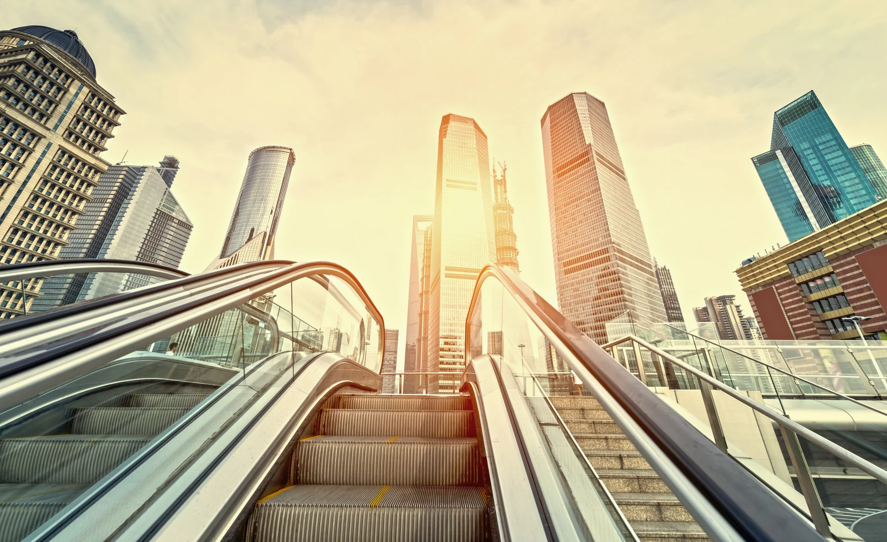 An escalator rising into Pudong's tower district, showing how daily movement happens beneath rather than above the skyline