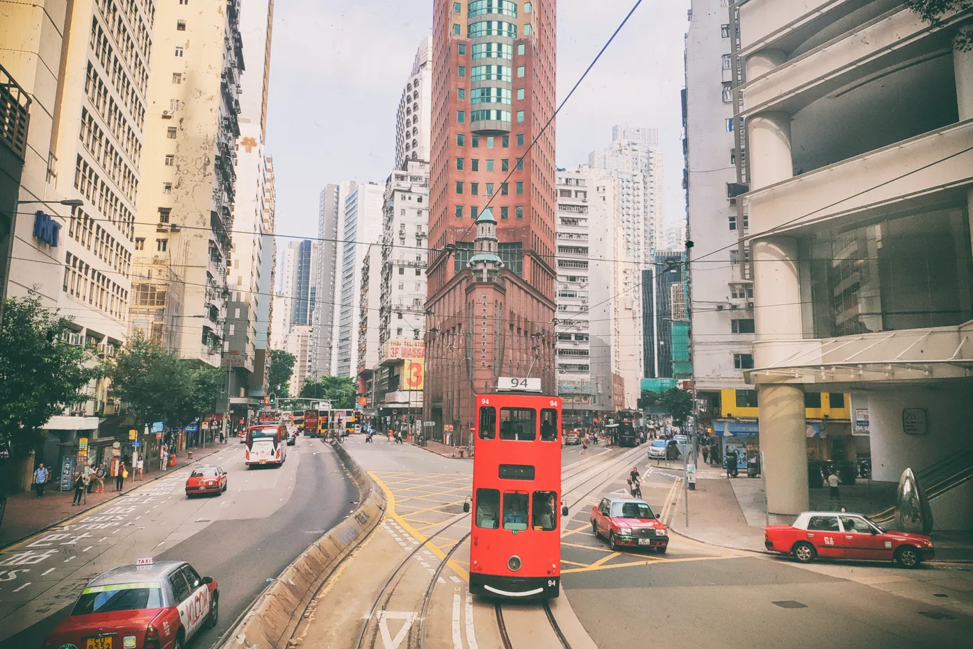 A red Hong Kong tram moving through contemporary street life