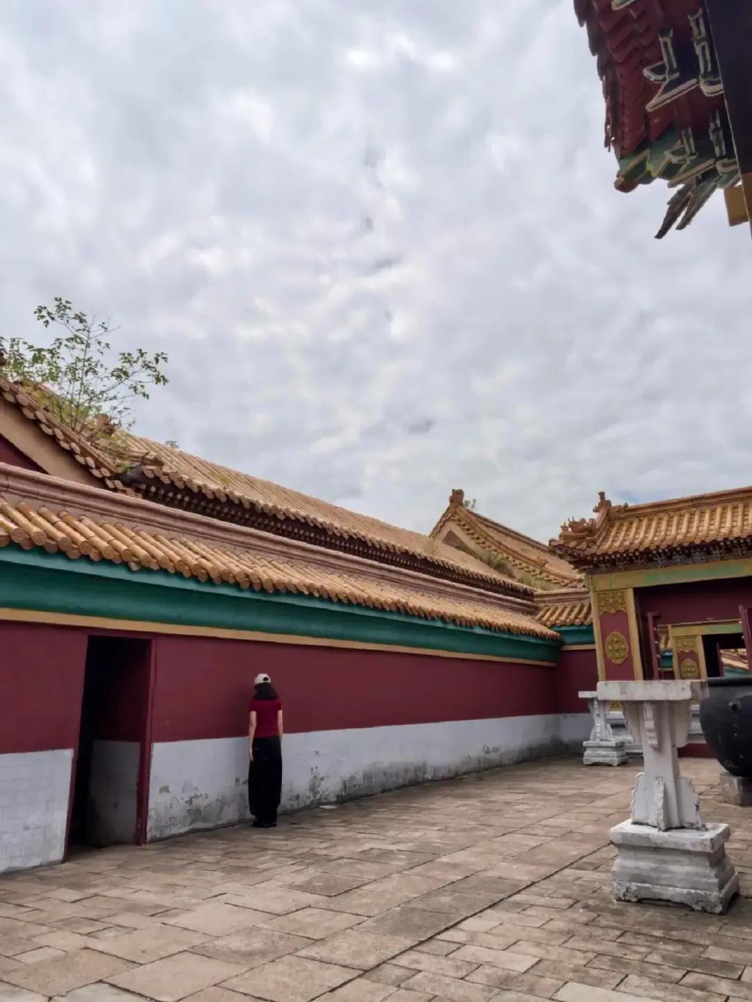 A quiet courtyard with red walls and layered tiled roofs inside the Qin Palace visitor area