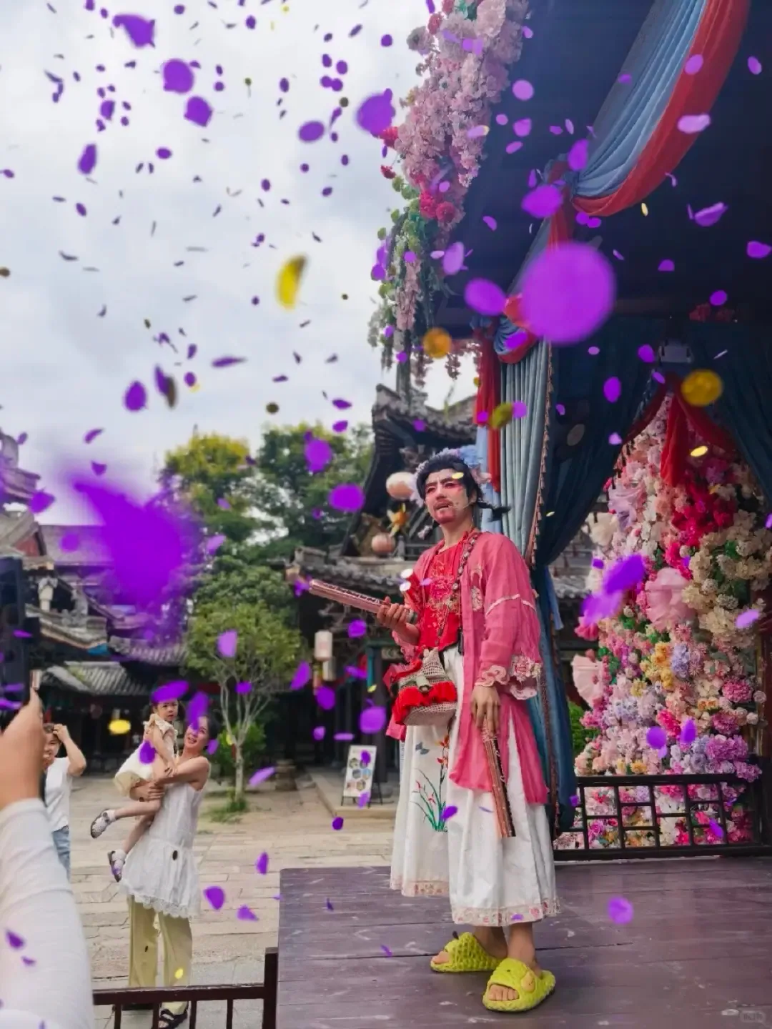 A street performer surrounded by visitors and falling confetti in the Qingming Shanghe Tu area